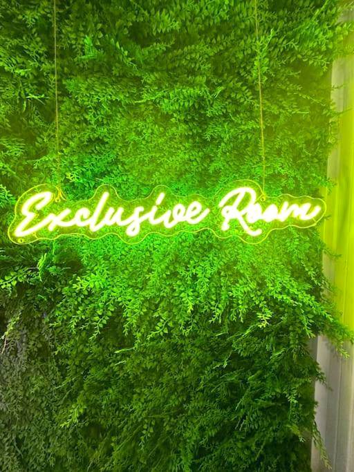 Enseigne néon Exclusive Room sur mur végétal - Exclusive Room BLOIS - Love Room