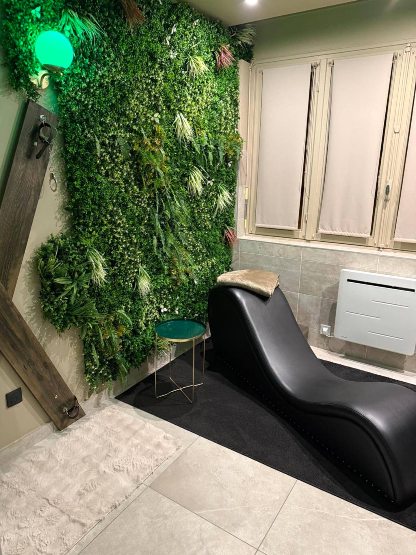 Fauteuil tantrique noir devant mur végétal - L'extasia appartement Grenoble