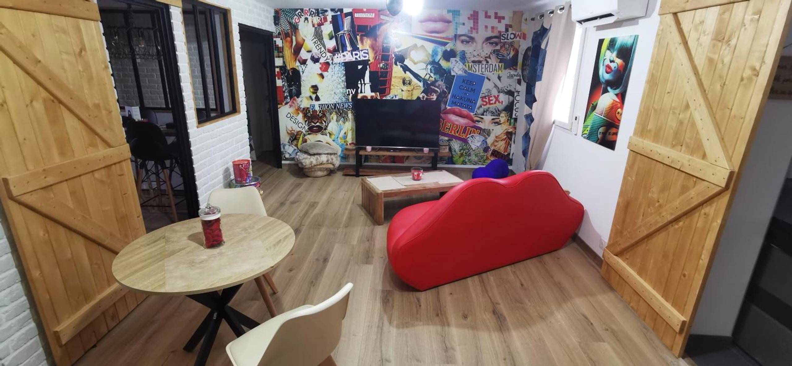 Salon avec canapé bouche rouge et mur décoré - Gîtes déco pop et chaleureuse avec jacuzzi, sauna, piece coquine