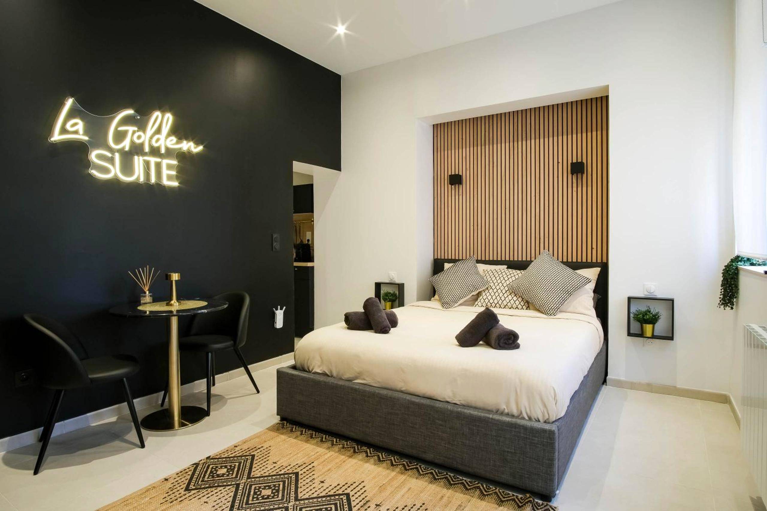 Chambre avec lit double et néon décoratif - La Golden Suite