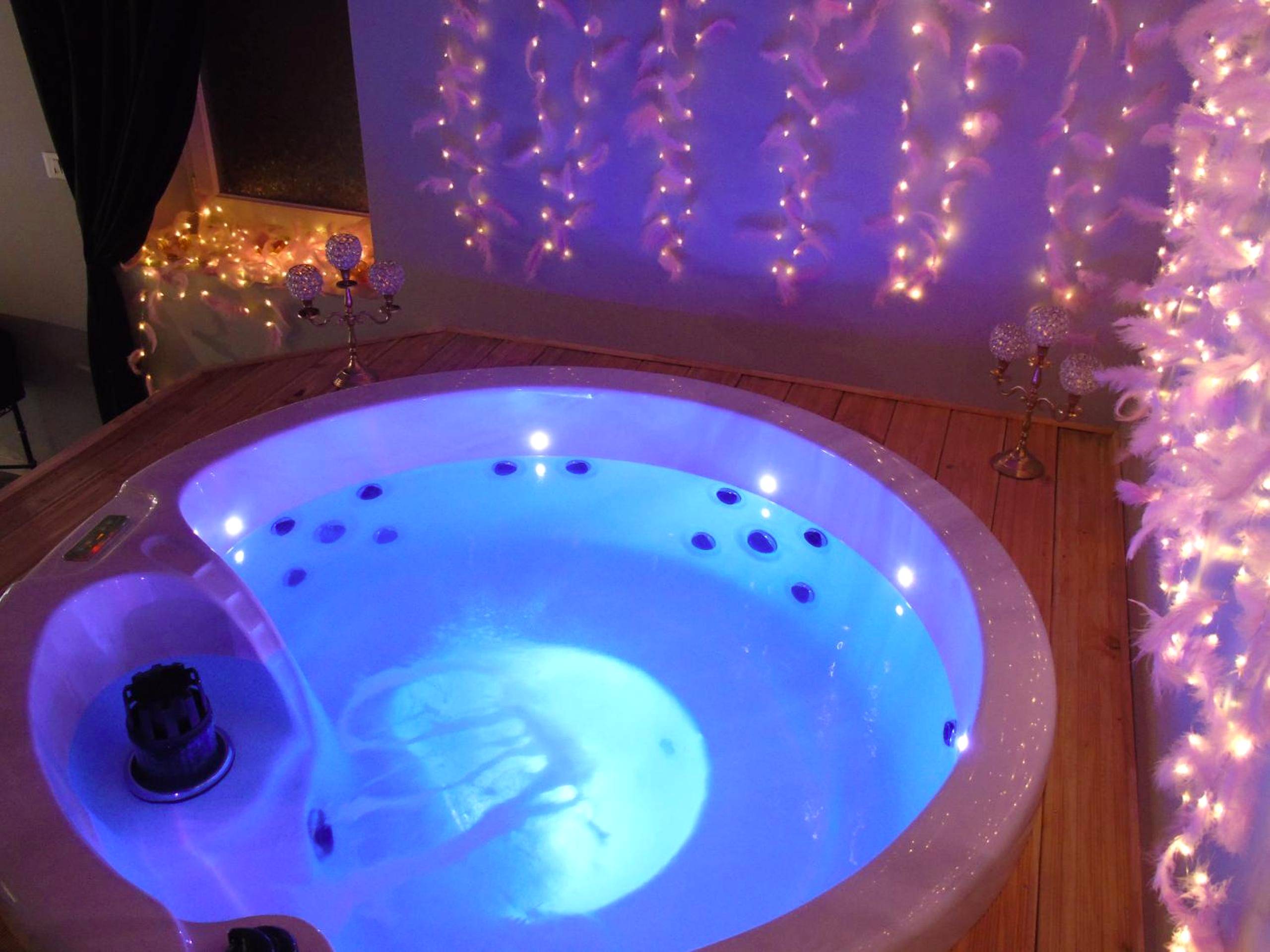 Jacuzzi rond avec éclairage bleu et guirlandes - love room La gondole du plaisir