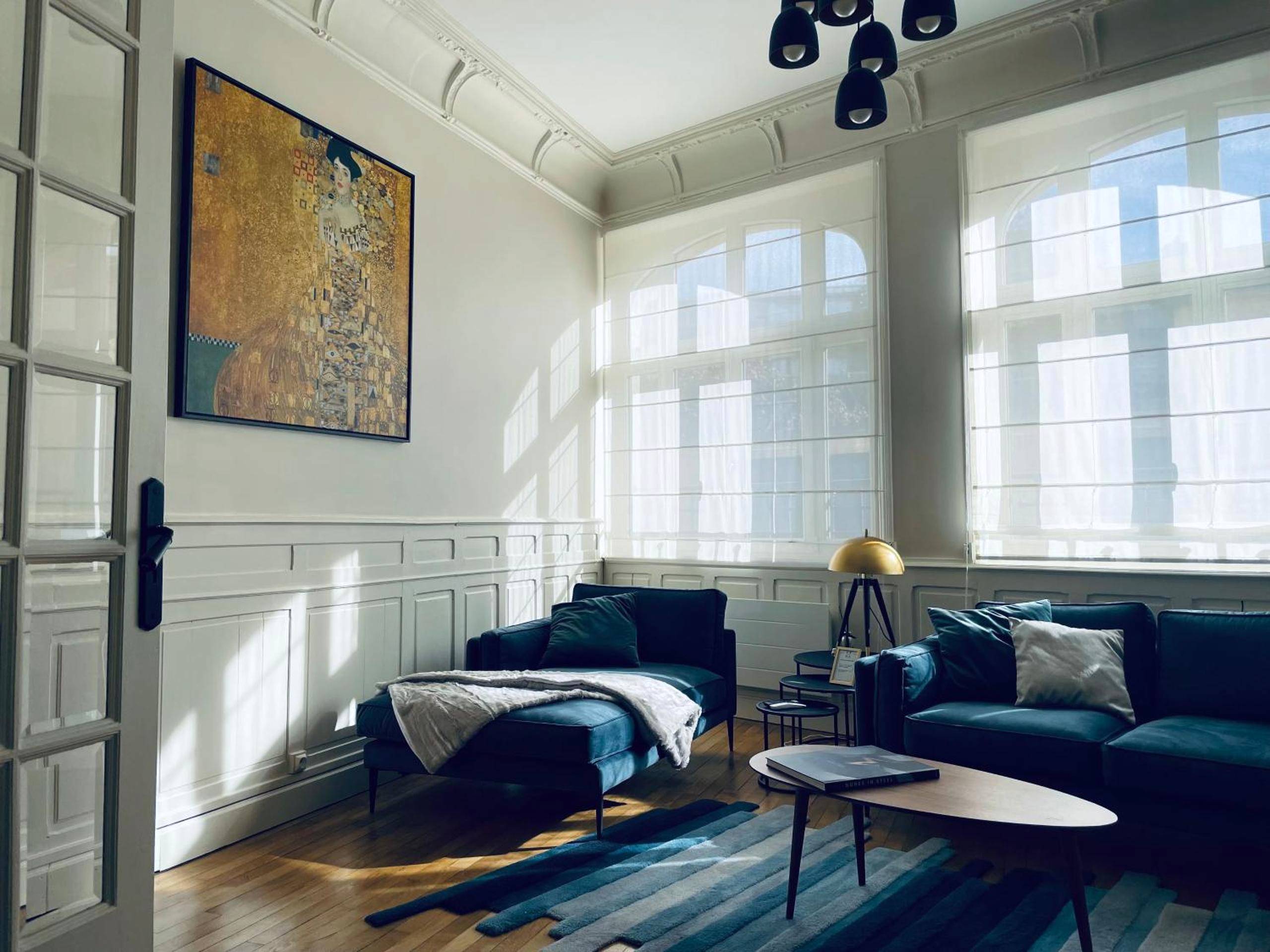 Salon lumineux avec canapés en velours bleu - Hédoné Suite de luxe et Spa privatif