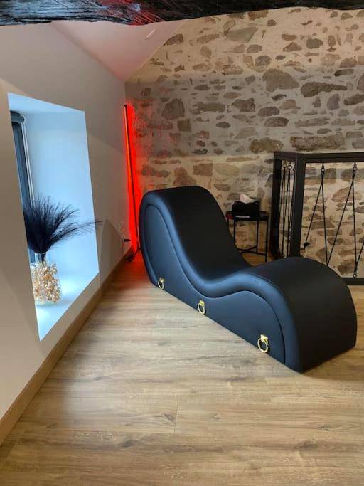 Fauteuil tantrique noir devant mur en pierre - Love Room Folles - La Home Love location de séduction