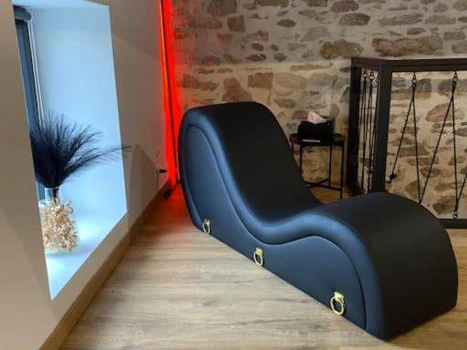 Fauteuil tantrique noir devant mur en pierre - Love Room Folles - La Home Love location de séduction