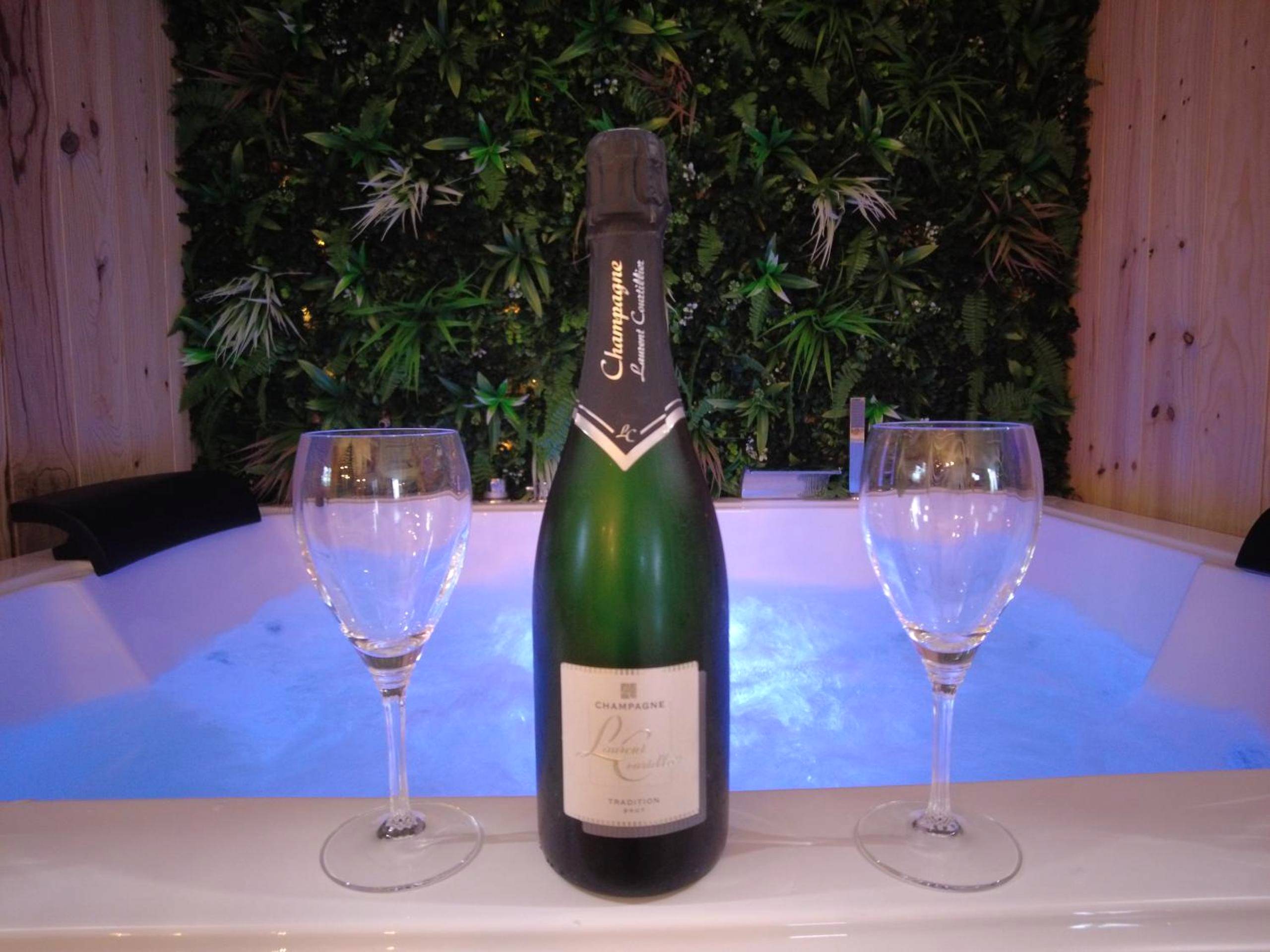 Bouteille de champagne devant jacuzzi éclairé - Love Room Reuilly - HOTEL DU BERRY - Loveroom avec Sauna, Hammam,...
