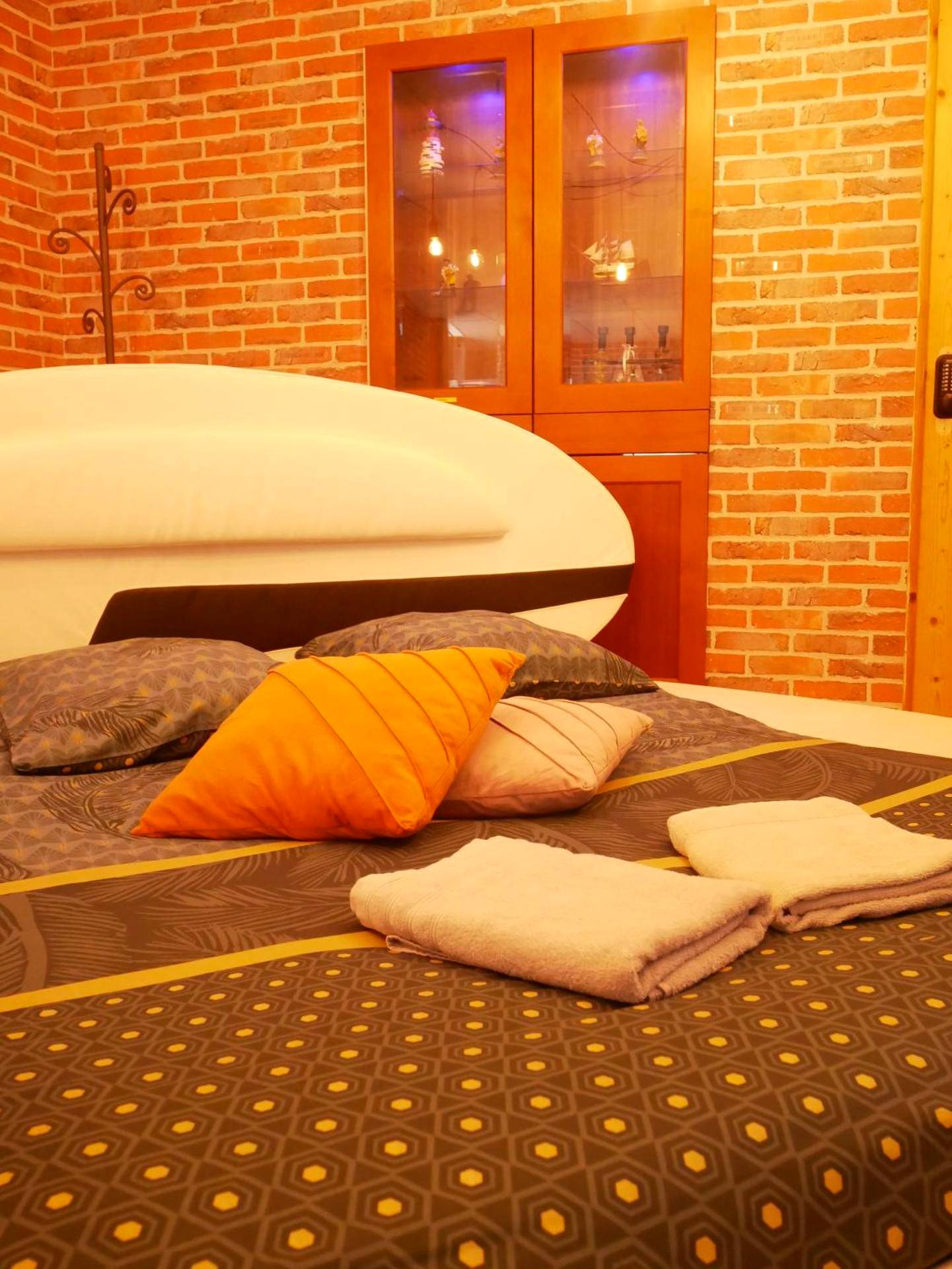 Lit double avec coussins et briques apparentes - HOTEL DU BERRY - Loveroom avec Sauna, Hammam, Jacuzzi privatifs