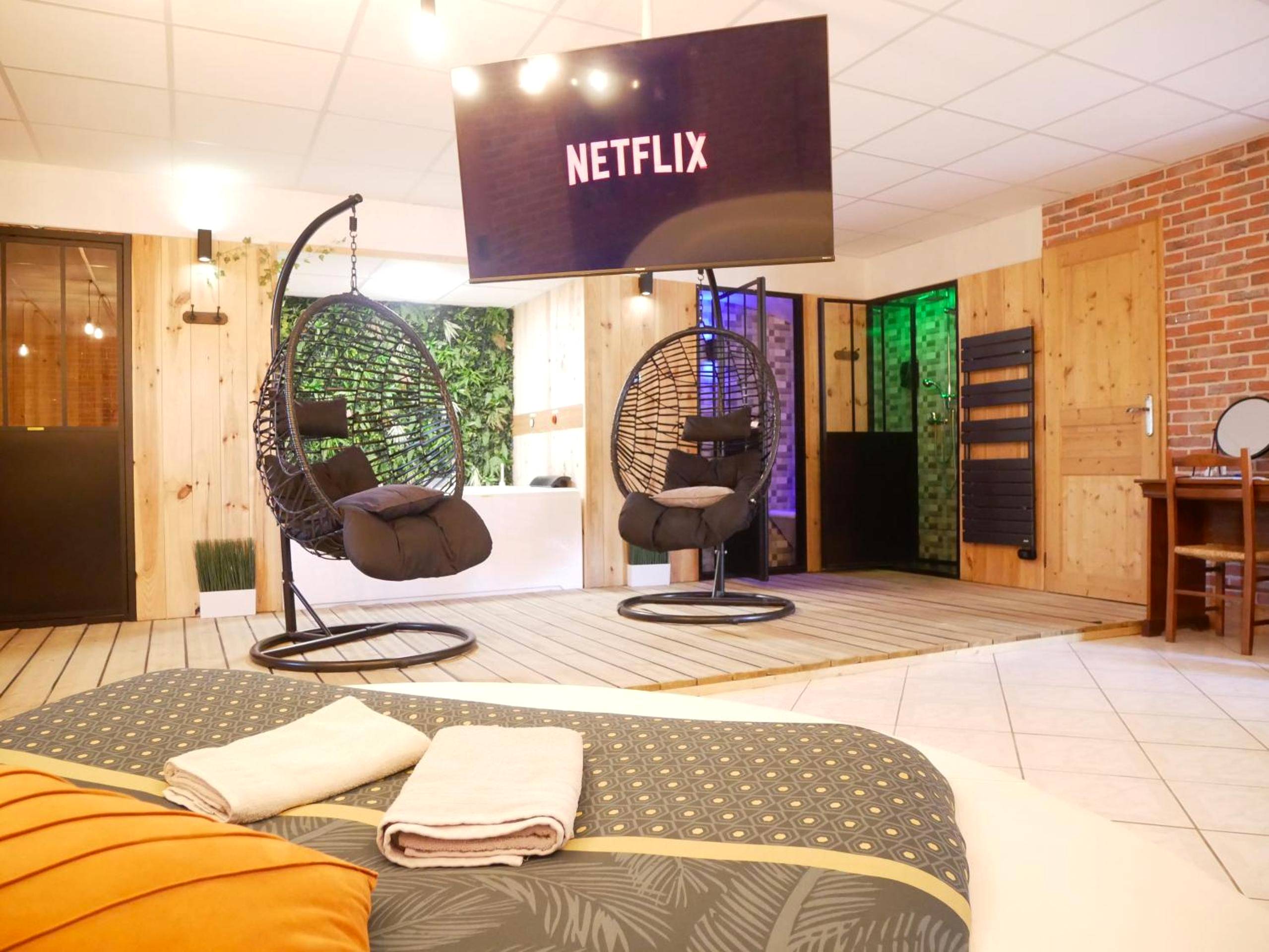 Fauteuils suspendus face à écran géant Netflix - HOTEL DU BERRY - Loveroom avec Sauna, Hammam, Jacuzzi privatifs