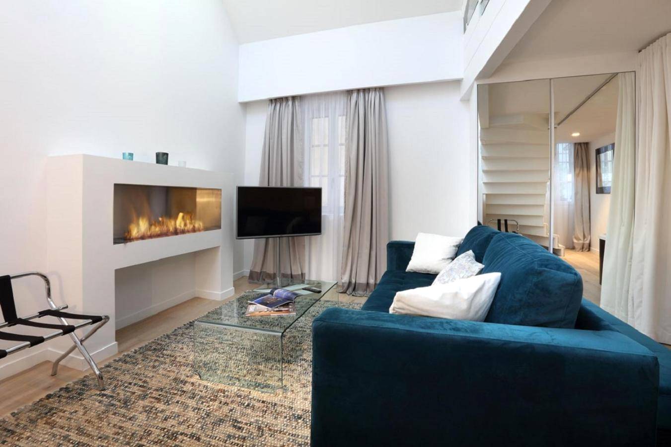 Salon avec canapé bleu et cheminée moderne - Petit Hôtel Confidentiel