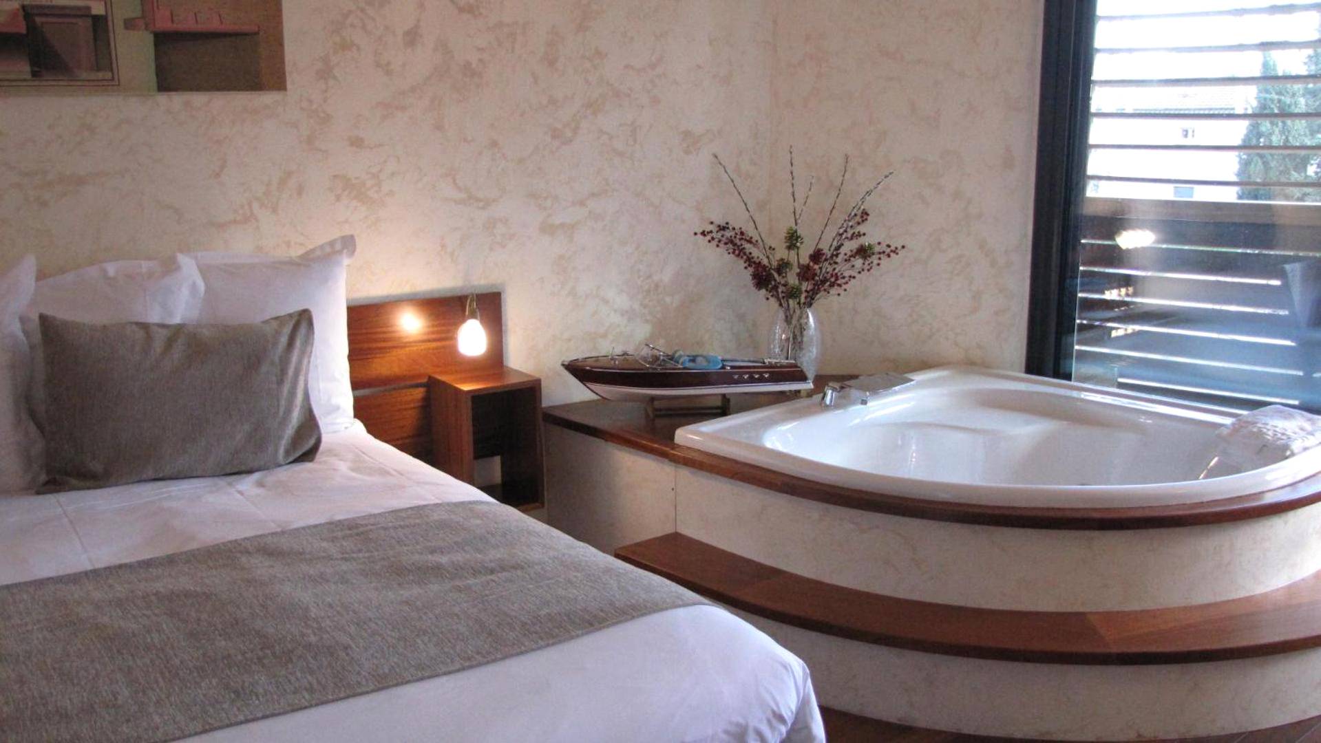 Baignoire balnéo à côté d'un lit double - Love Room Narbonne - Ile du Gua Suites