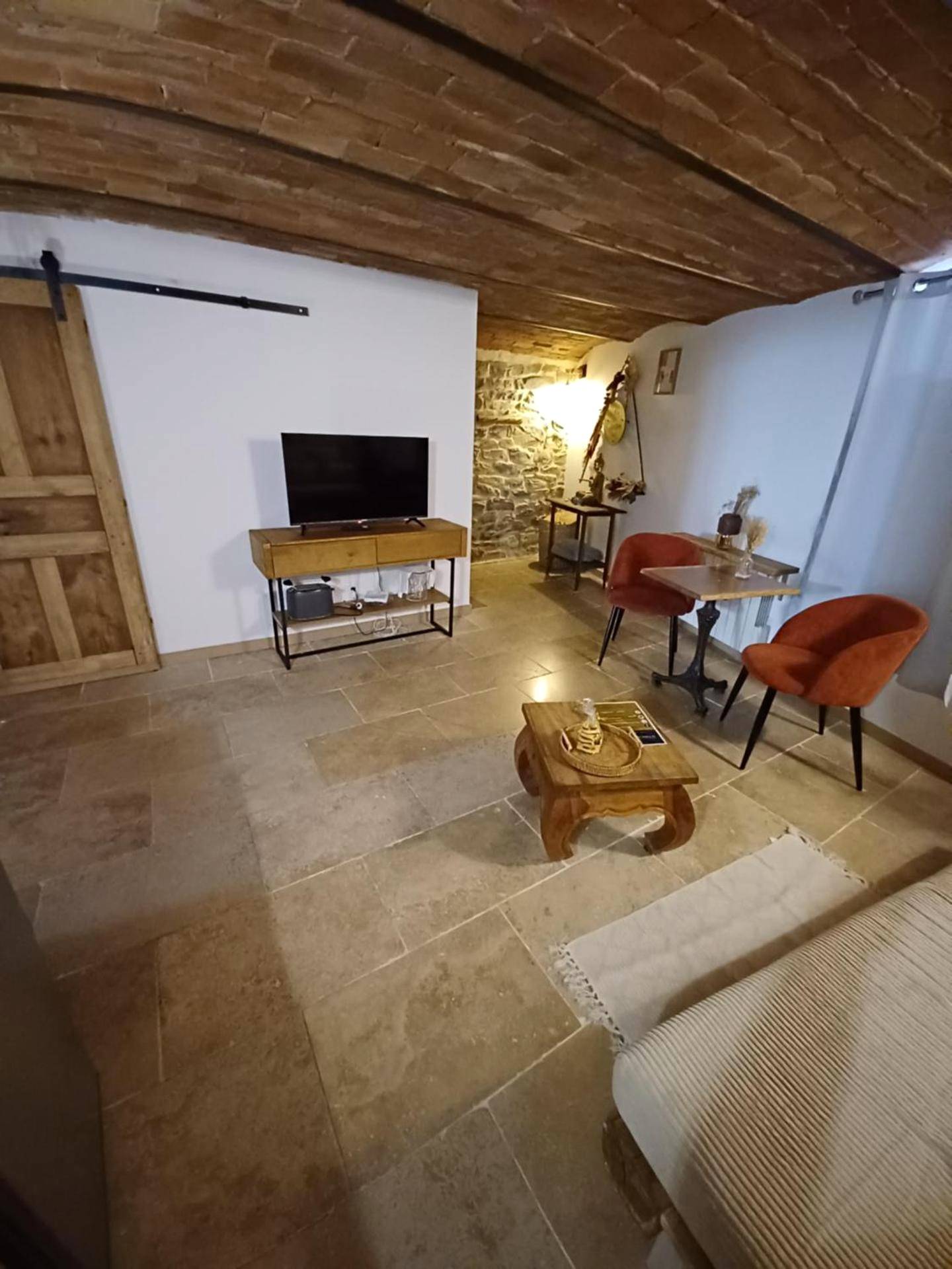 Salon avec télévision et fauteuils orange - Hébergement insolite avec jacuzzi privatif Millau