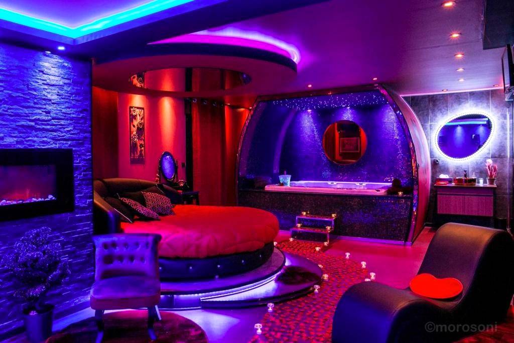 Lit rond rouge et jacuzzi sous néons violets - Love Room Toulouse - L'Insolite Spa Privatif ''Suite Luxueuse - Jacuzzi"