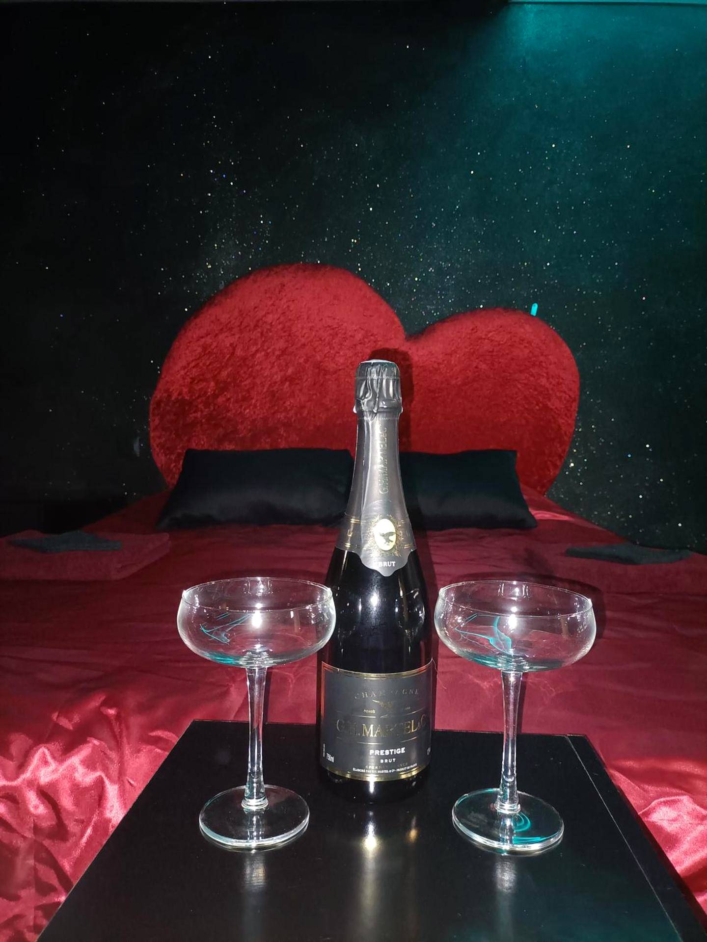 Bouteille de champagne et coupes devant le lit - L'instant romance Le Romantique