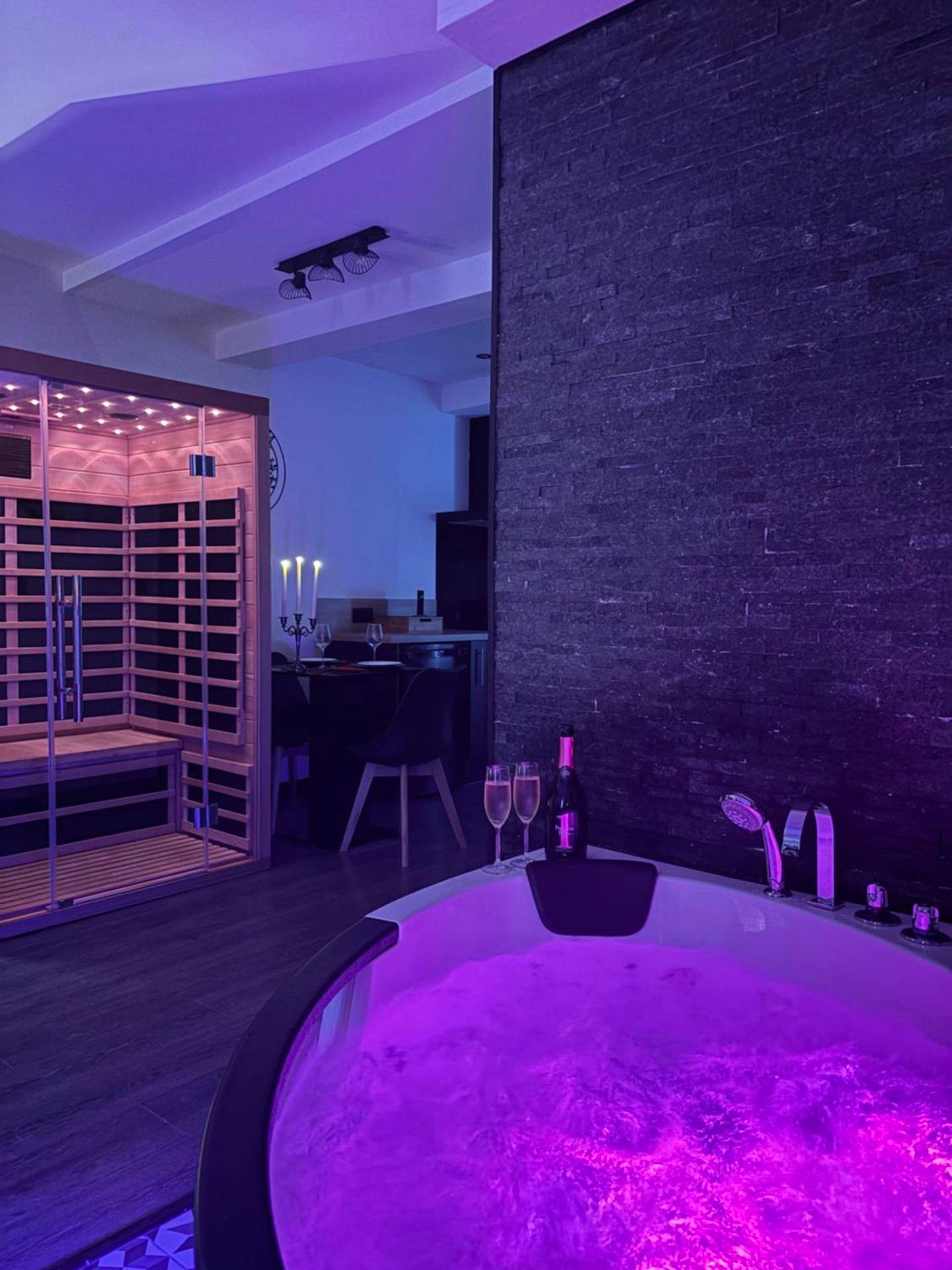 Jacuzzi et sauna avec éclairage tamisé violet - Love Room Limoux - Love Room L'instanté - Suite "L'élégante"