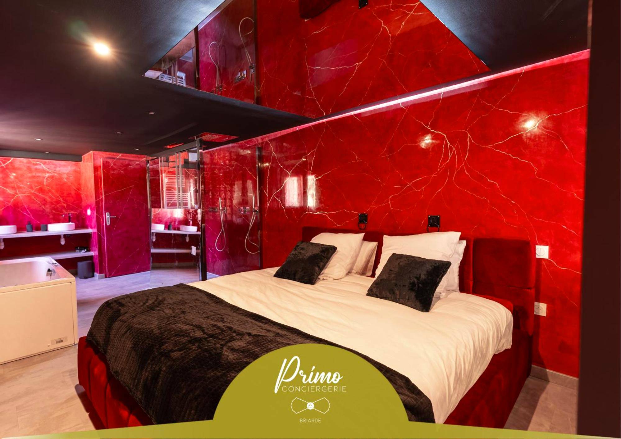 Lit double devant un mur en marbre rouge - Love Room La Ferté - Gaucher - L'Interdit, Confort et Sensualité