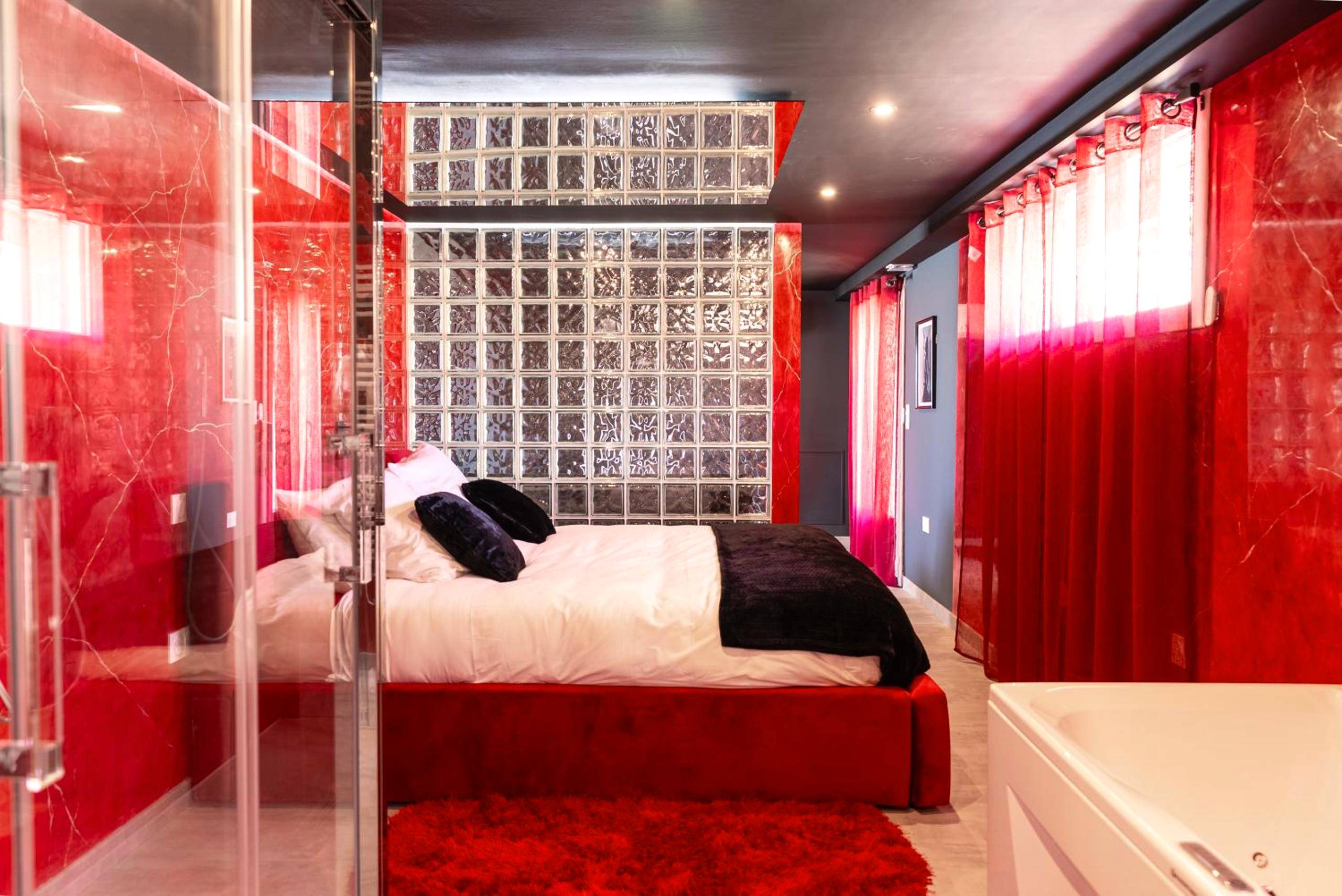 Chambre avec briques de verre et tapis rouge - L'Interdit, Confort et Sensualité
