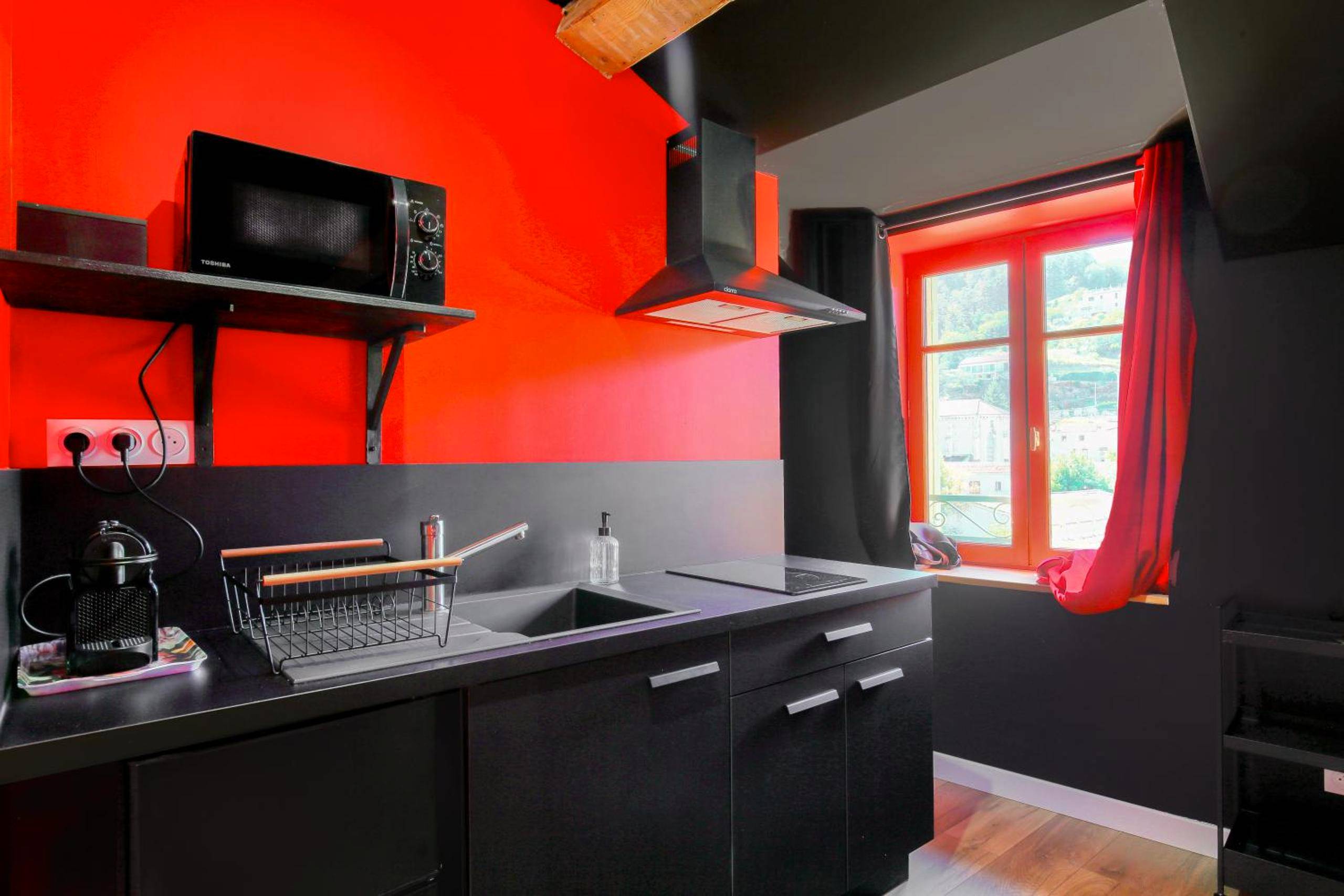 Kitchenette équipée moderne noire et rouge - L'Interdit Suite Luxe Romantique Spa Balneo Sauna Hammam
