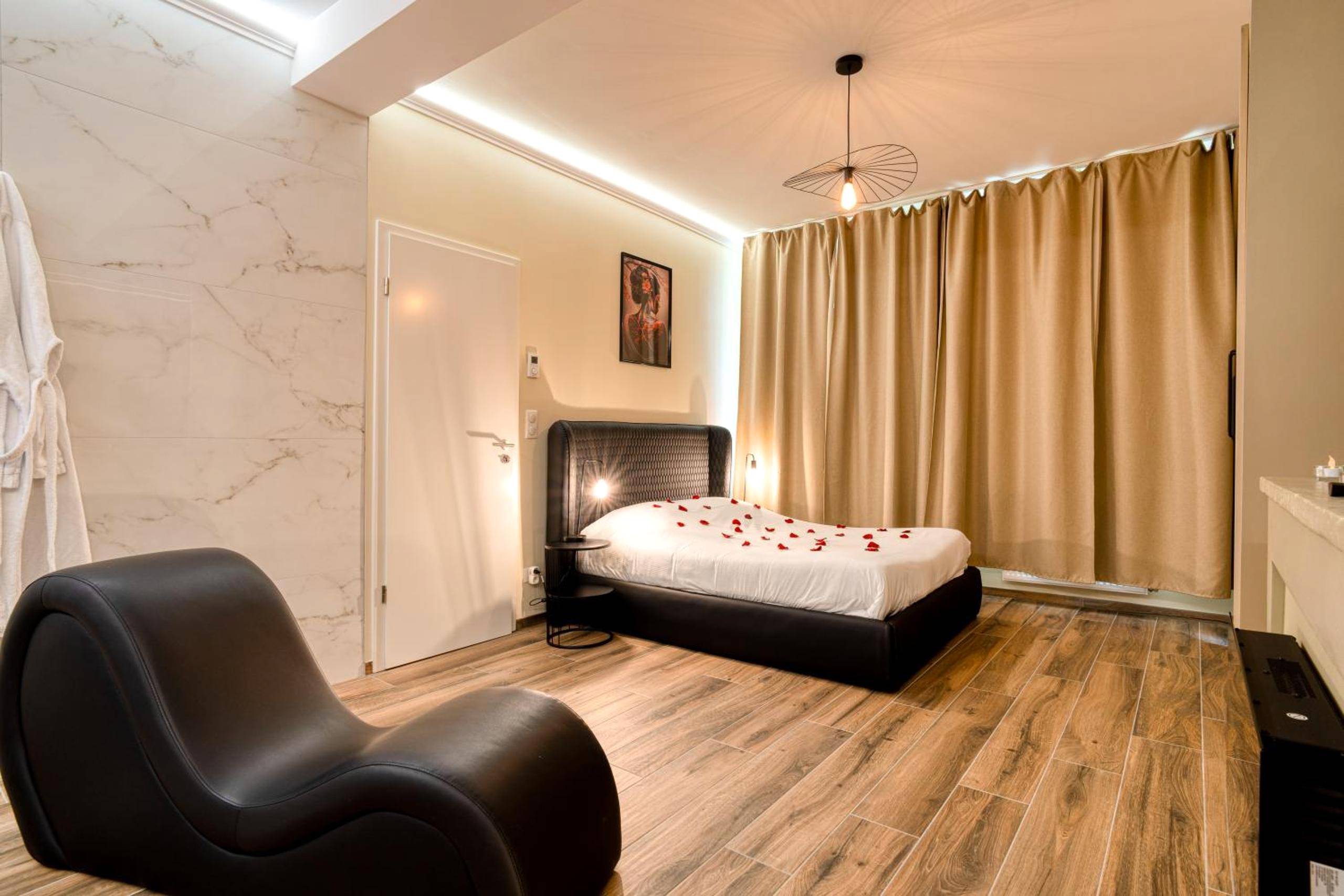 Lit double avec pétales de rose et fauteuil - Intime Spa et Sauna au coeur de Metz