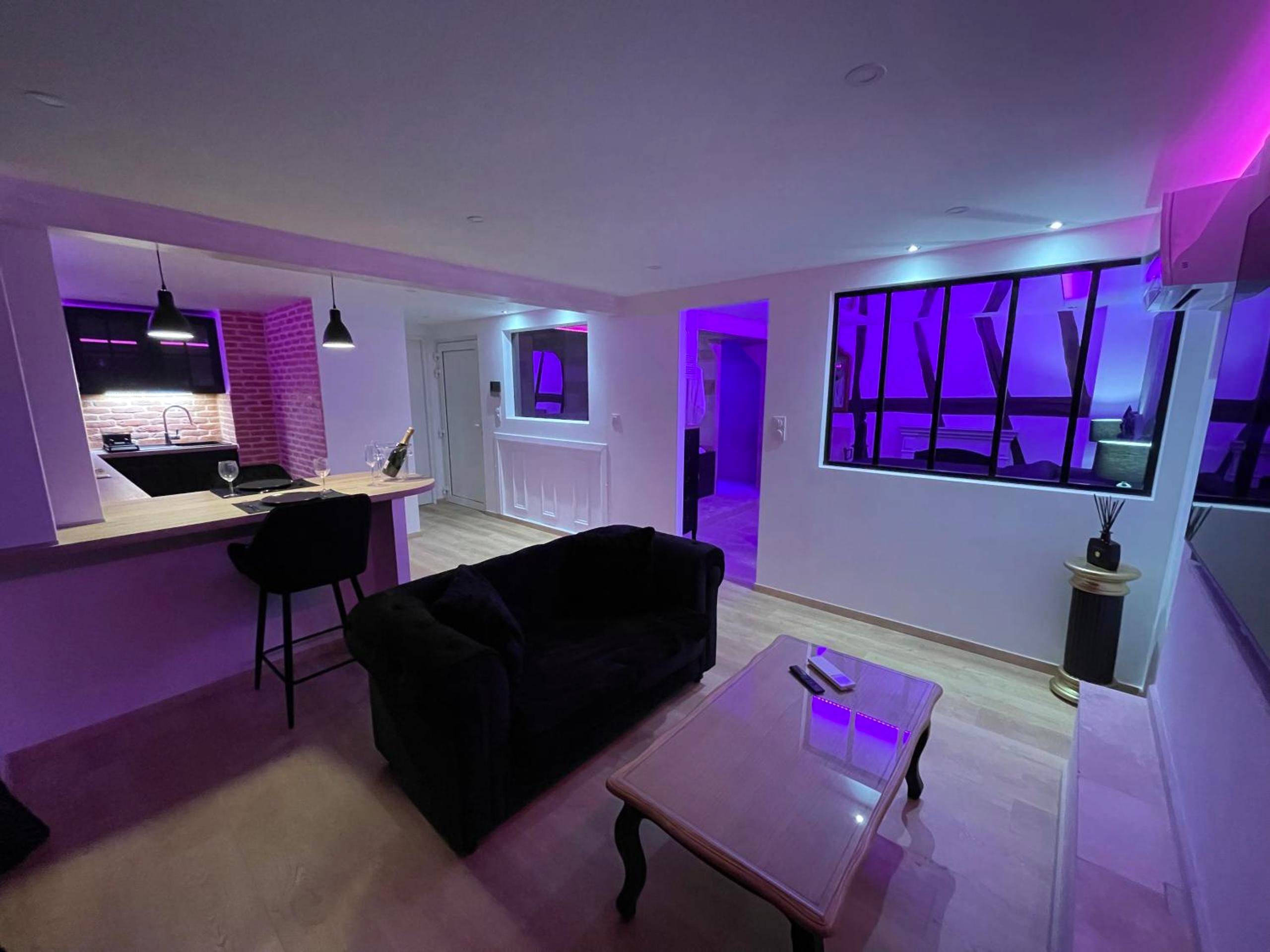 Salon avec canapé noir et coin cuisine - Le Jacuzzi