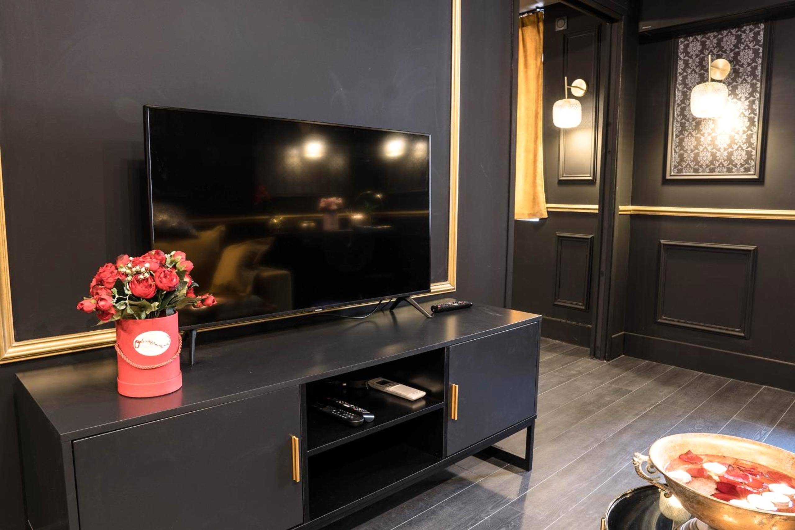 Téléviseur sur meuble noir et fleurs rouges - Superbe Appartement avec Jacuzzi...