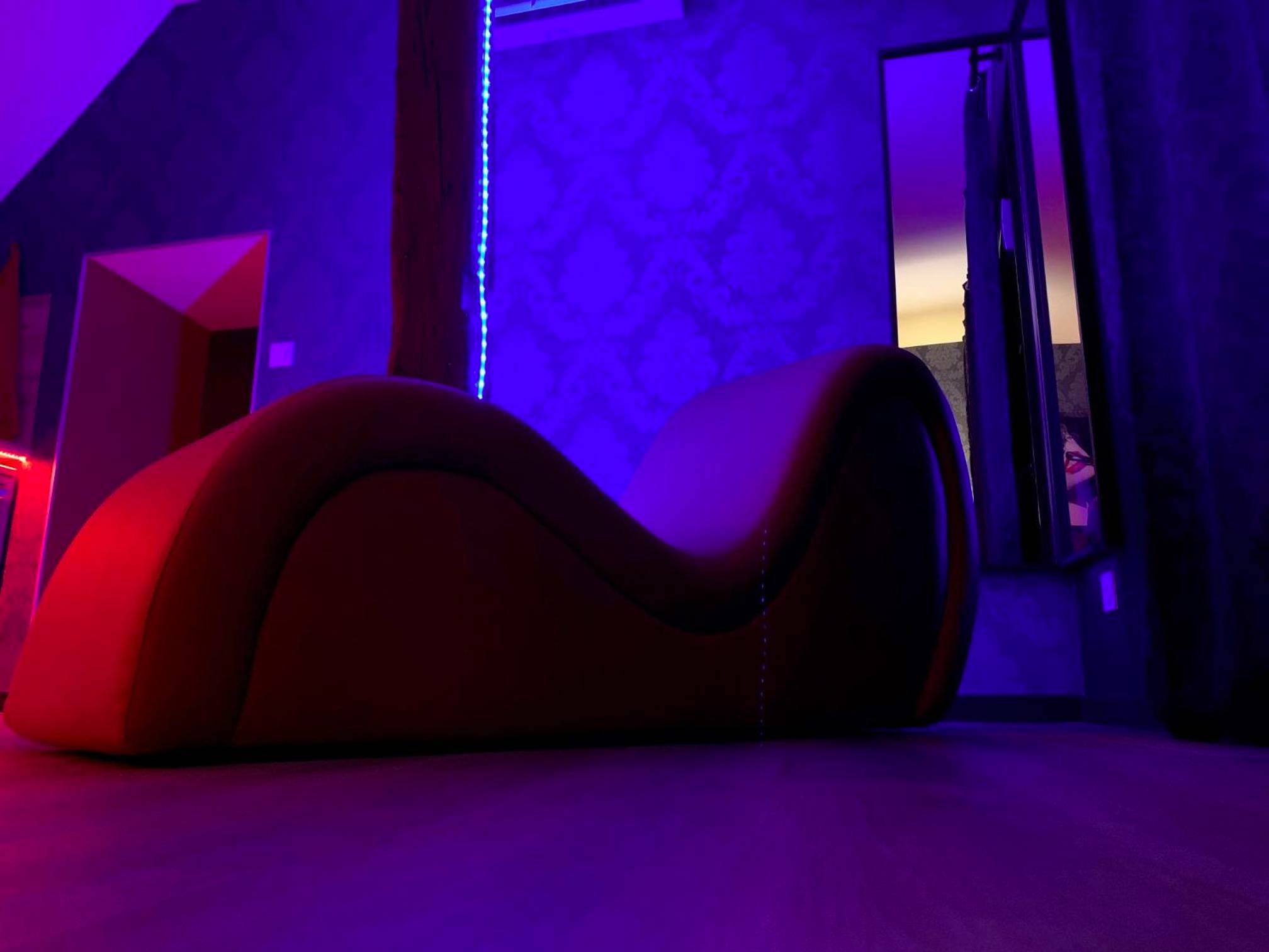 Divan de massage rouge sous lumière bleue - Love room avec jacuzzi privé