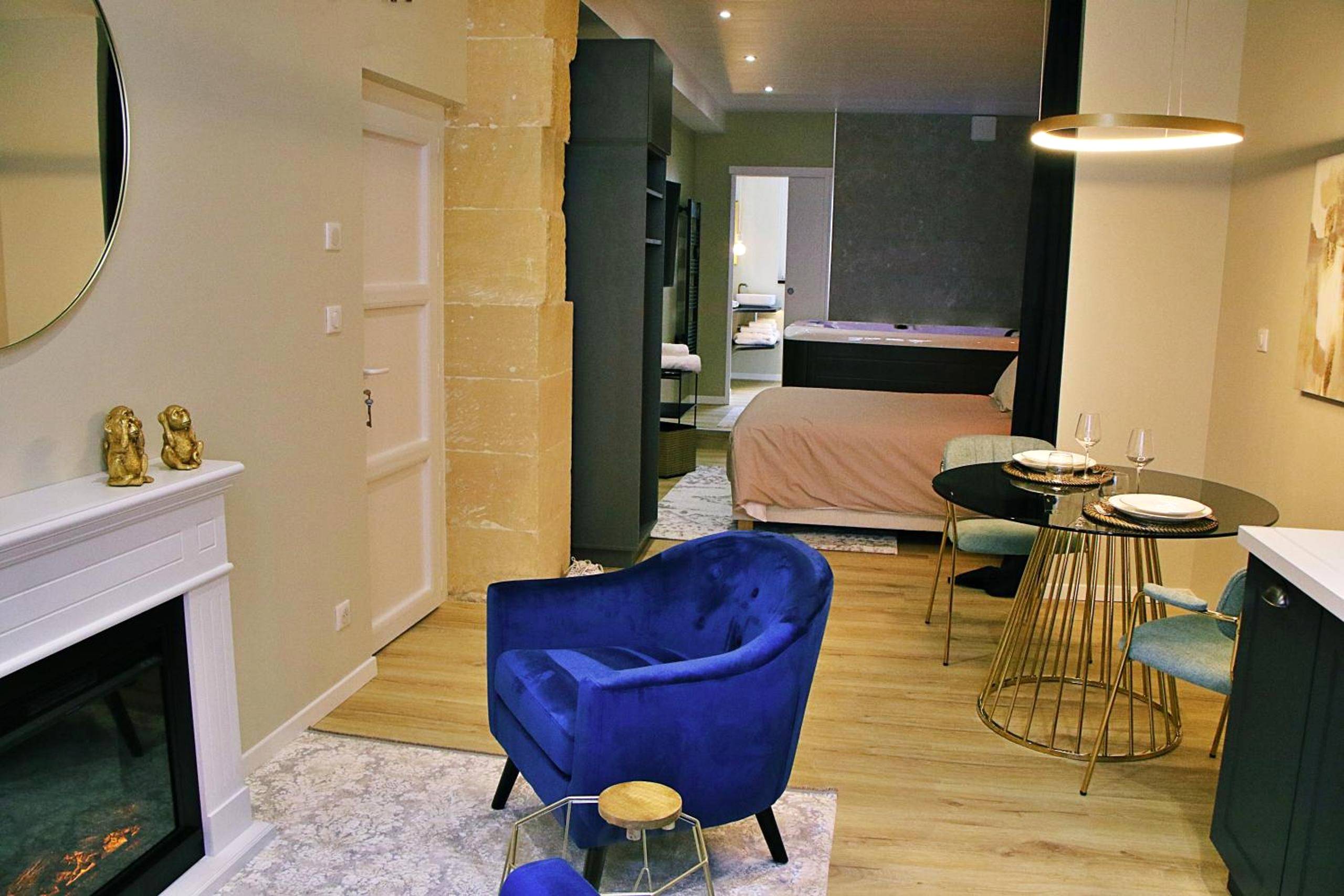 Salon avec fauteuil bleu et cheminée - Appartement luxueux avec Jacuzzi privatif