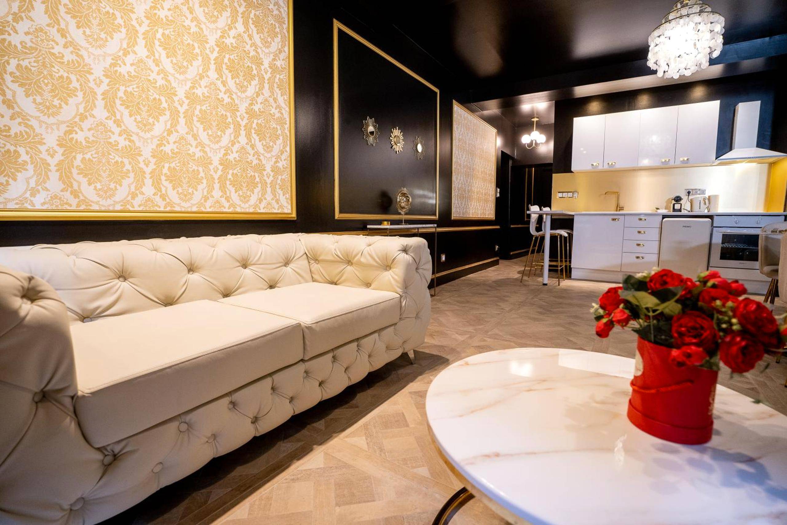 Salon avec canapé capitonné et cuisine équipée - Love Room Villefranche - sur - Saône - Appartement d'exception avec Jacuzzi
