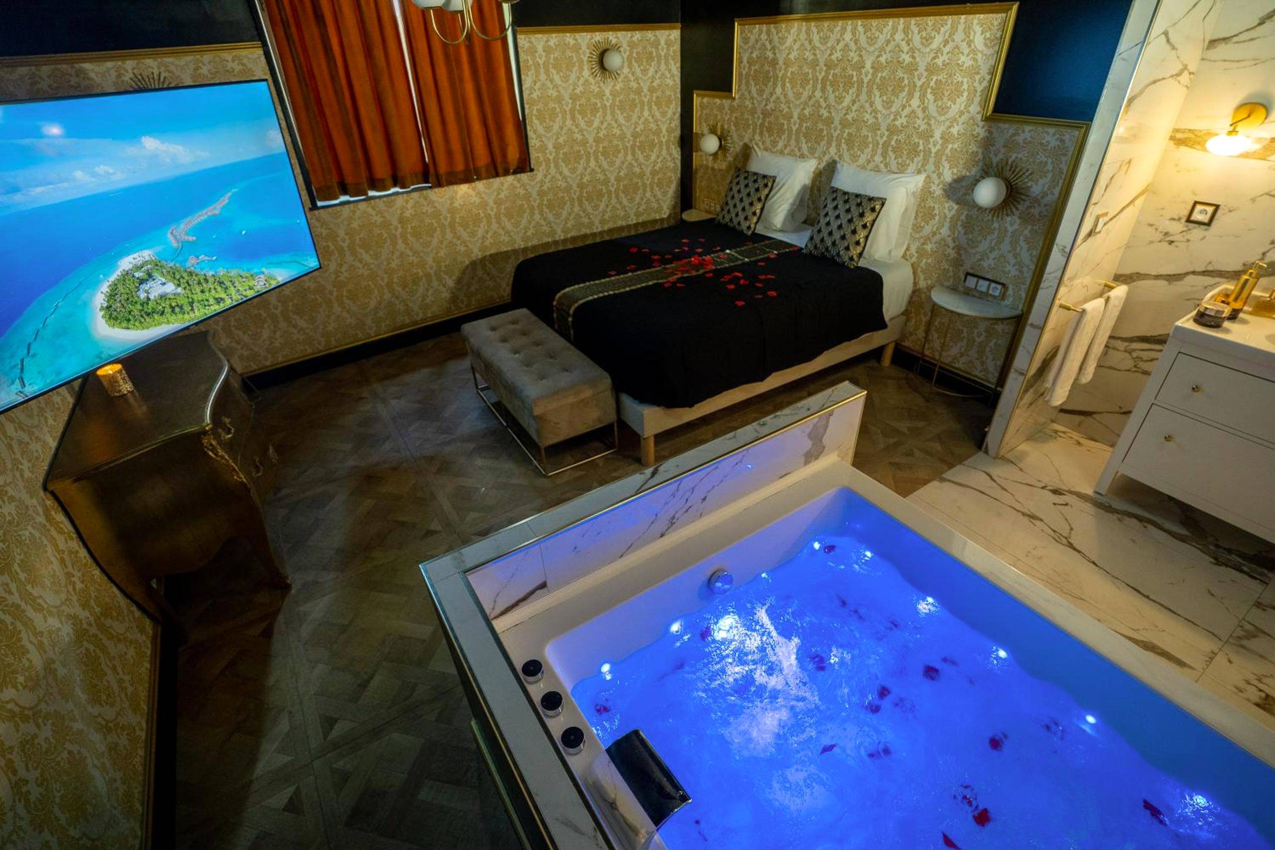 Jacuzzi éclairé en bleu et lit avec pétales - Appartement d'exception avec Jacuzzi