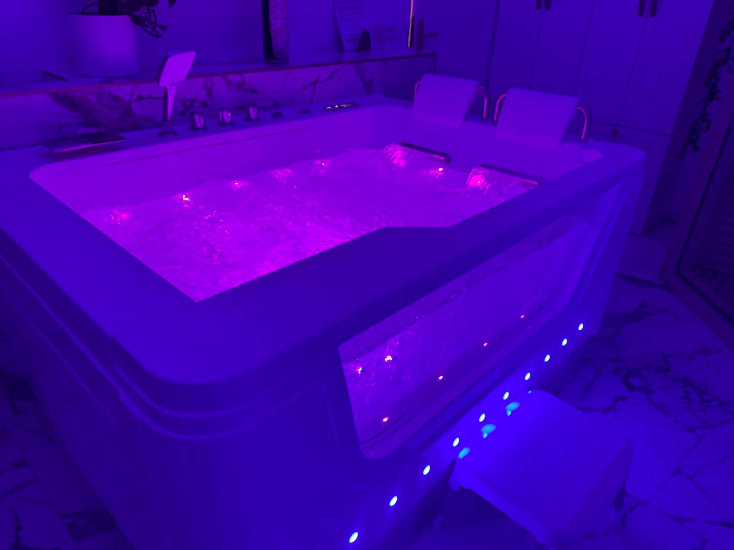 Jacuzzi privatif avec éclairage néon violet - Love Room Metz - Loveroom de luxe avec jacuzzi sauna vapeur écran 300 cm