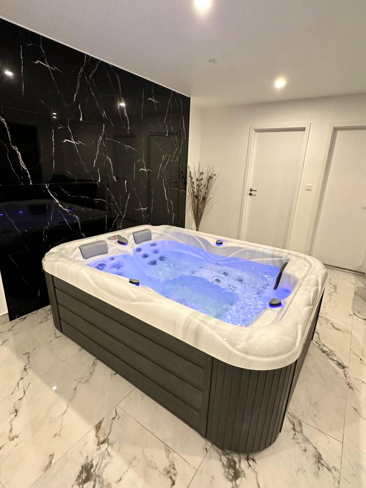 Jacuzzi avec éclairage bleu et mur en marbre - Appartement cosy jacuzzi spa 70M2