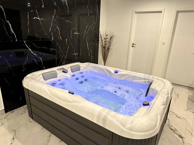 Jacuzzi avec éclairage bleu et mur en marbre - Appartement cosy jacuzzi spa 70M2