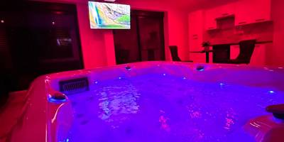 Jacuzzi illuminé sous une ambiance rose néon - Appartement cosy jacuzzi spa 70M2