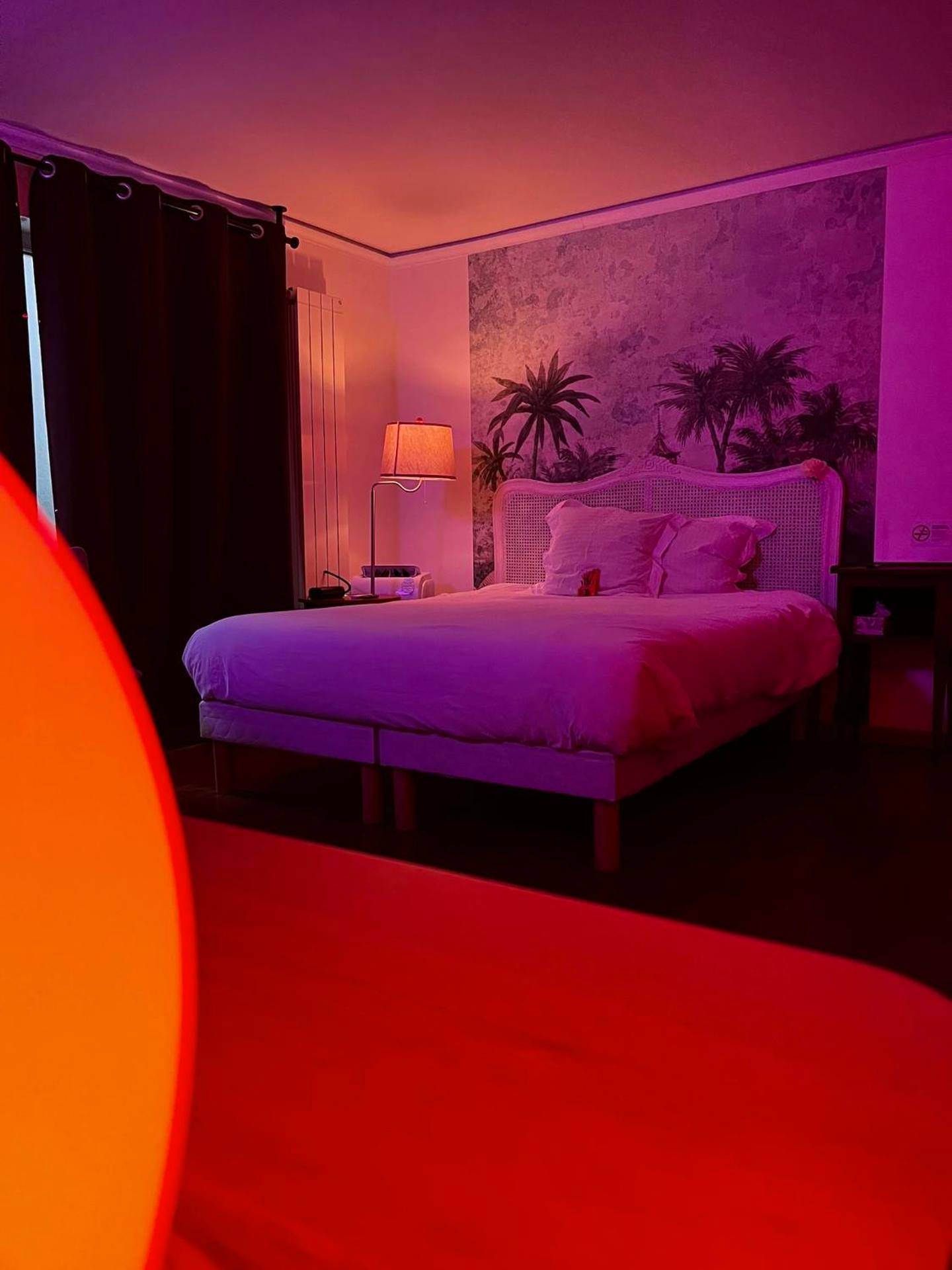 Lit double sous une lumière tamisée rose - Jacuzzi LOVE Suite