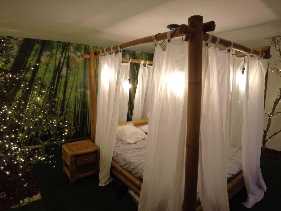 Lit à baldaquin en bambou avec voilages blancs - Love Room Issoudun - Le Jardin d'Eden - Appartement de charme avec...
