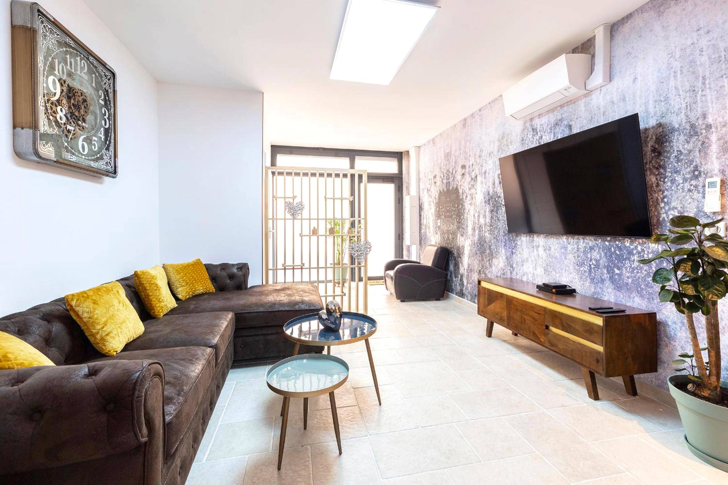 Salon avec canapé d'angle et grand écran TV - Le Jardin secret