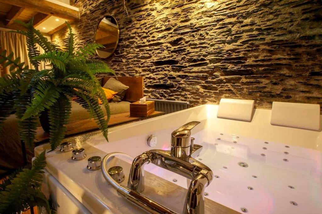 Jacuzzi privatif et mur en pierres apparentes - Love Room Angers - LOVE ROOM JUNGLE - LES PETITS PLAISIRS