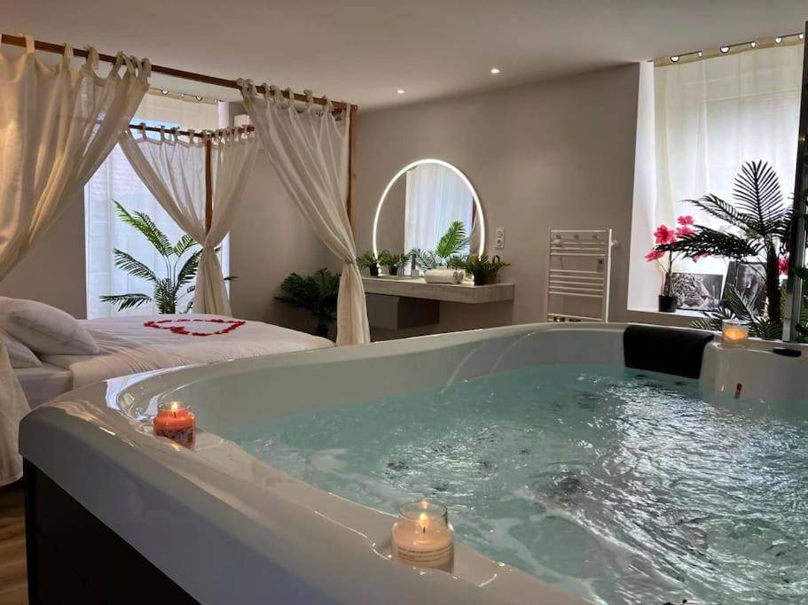 Jacuzzi privatif avec bougies et lit à baldaquin - Love Room Tergnier - Jungle Secret SPA Nuit insolite