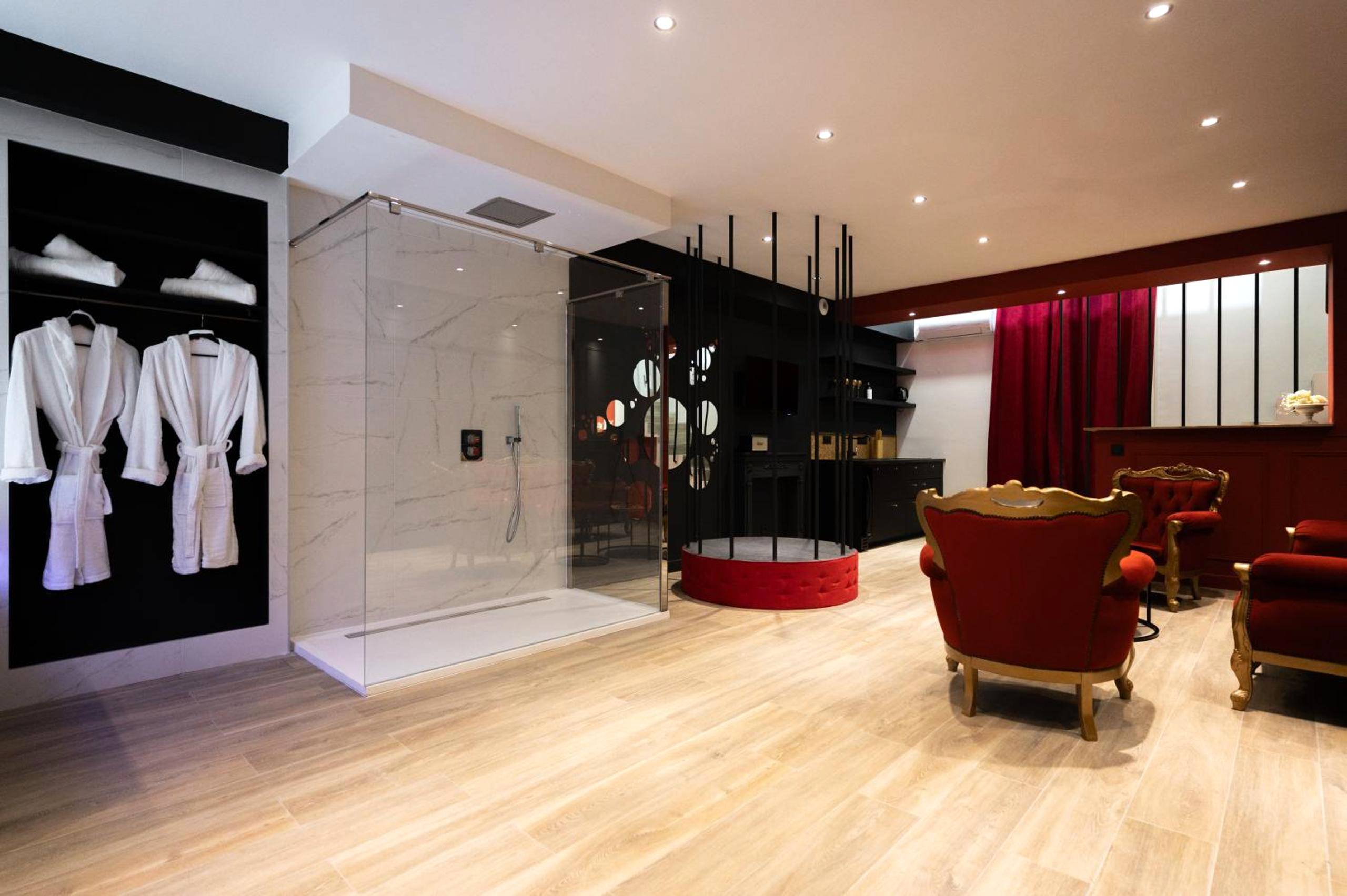 Salon avec fauteuils rouges et douche vitrée - Love Room Agde - LaPerleNoire Love Room XXL