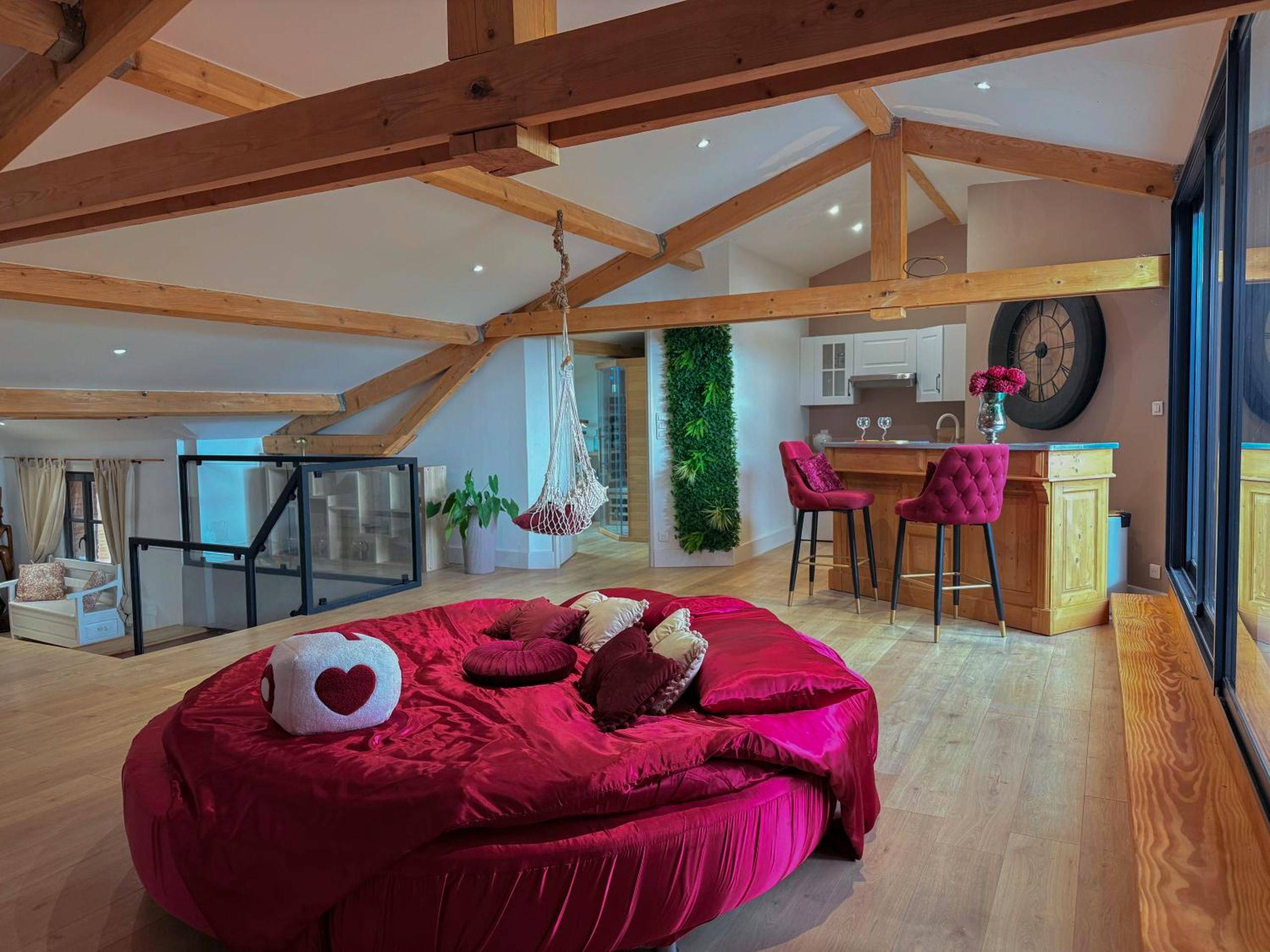 Lit rond en velours rouge sous charpente bois - Love Room Montauban - Le Loft Paradise