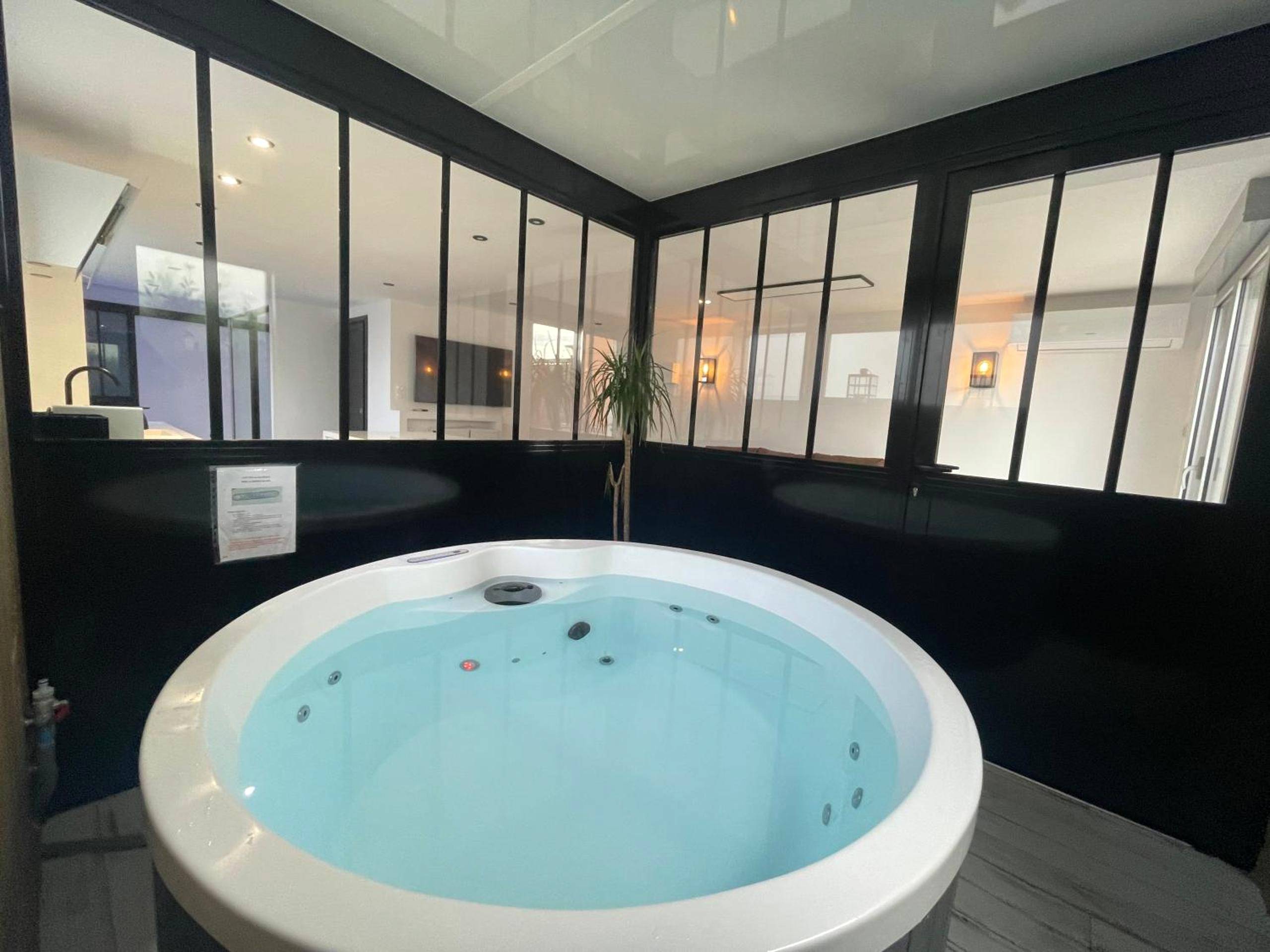 Jacuzzi rond intégré dans une verrière noire - Love Room Saint - Cyprien - Loft red lights