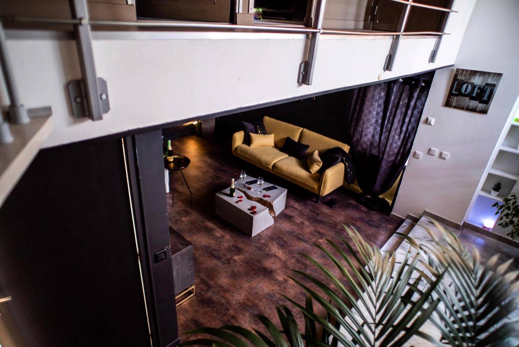 Vue en surplomb du salon avec canapé jaune - LOVE Suites & SPA "Le Loft" avec Jacuzzi privatif