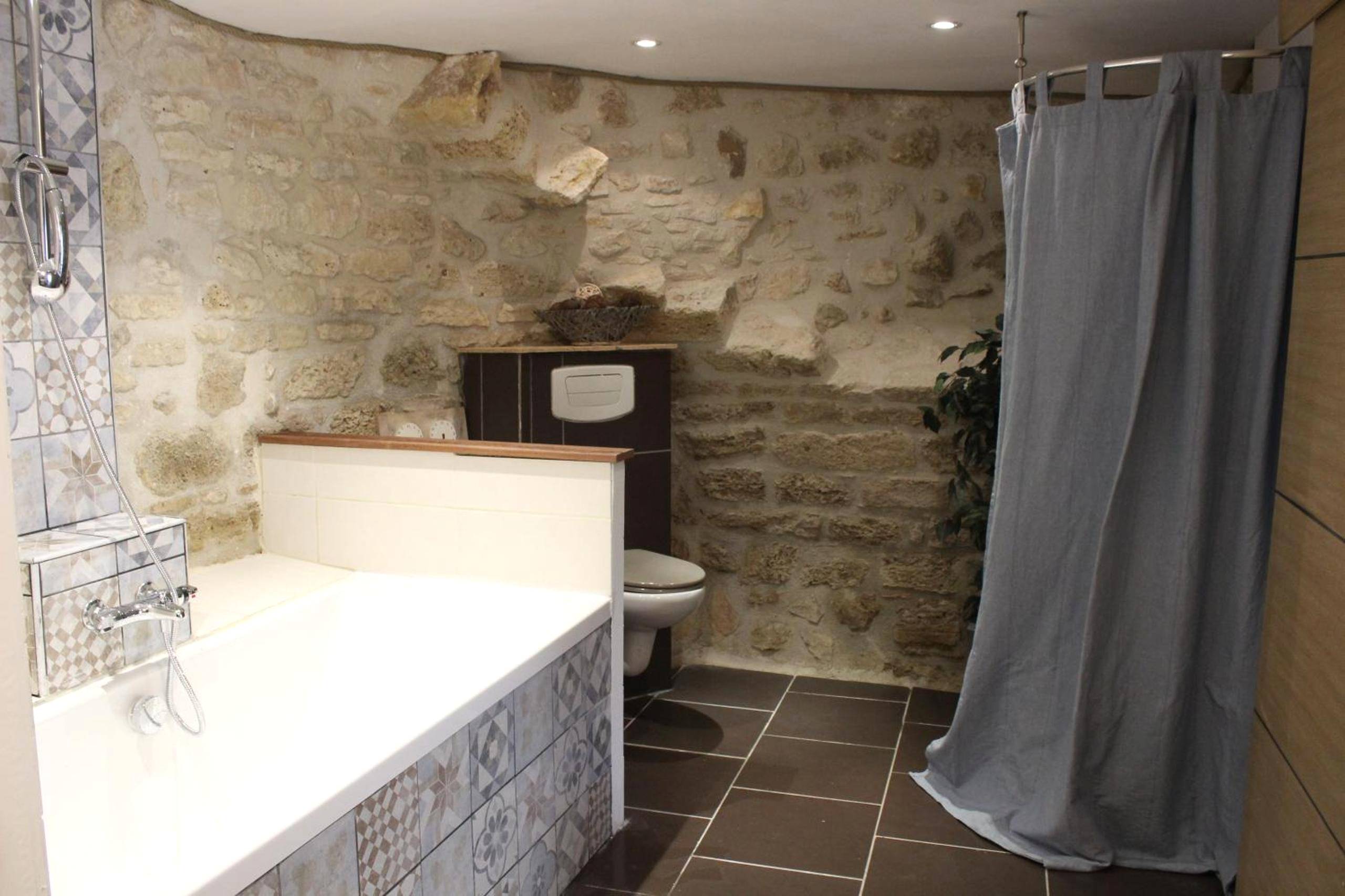 Salle de bain avec baignoire et murs en pierre - Gîte Lorengrain