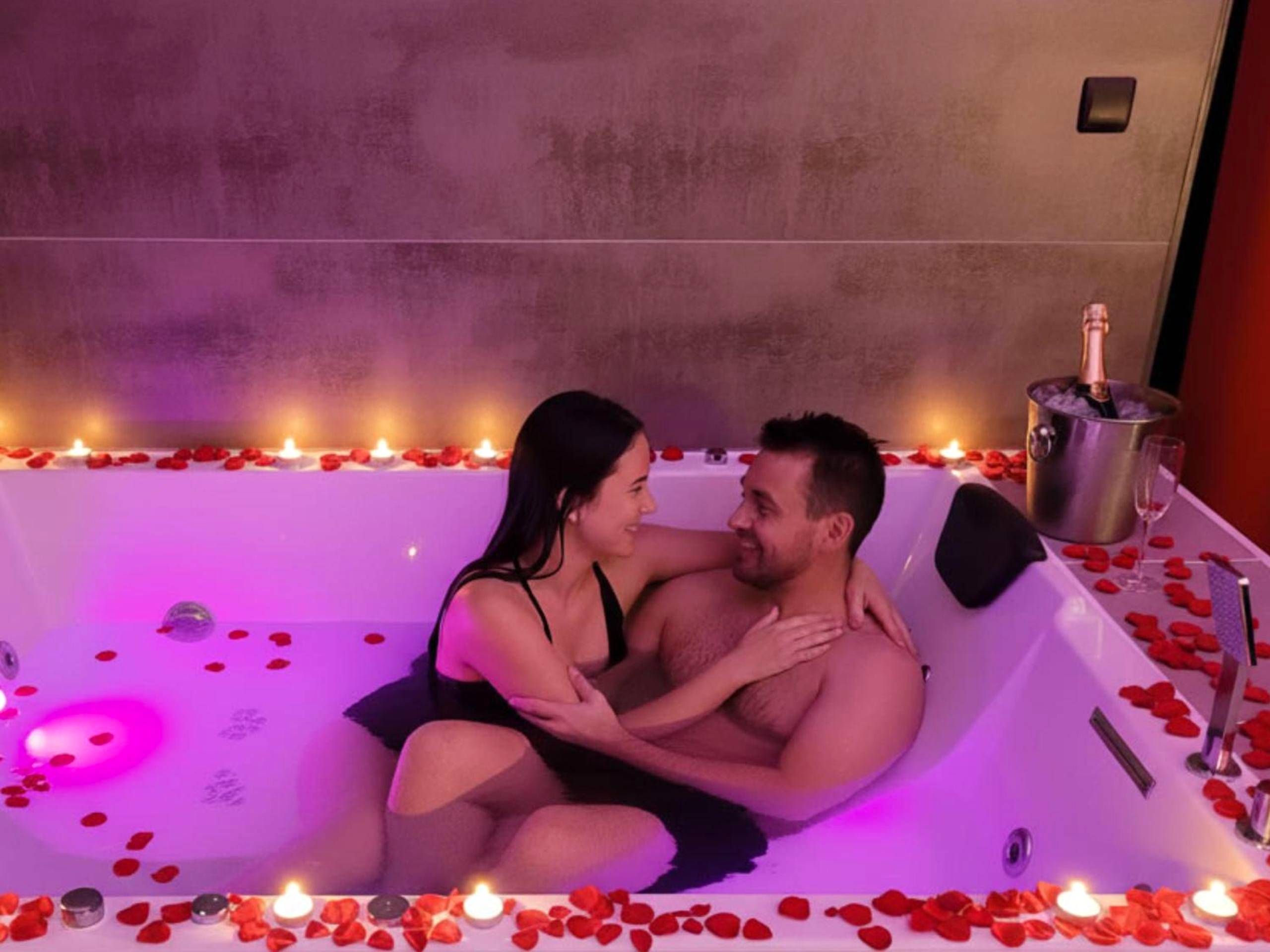 Couple dans un jacuzzi avec pétales et bougies - Love Room Avignon - Love & Spa