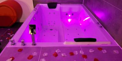 Jacuzzi privatif avec éclairage rose et pétales - Love & Spa
