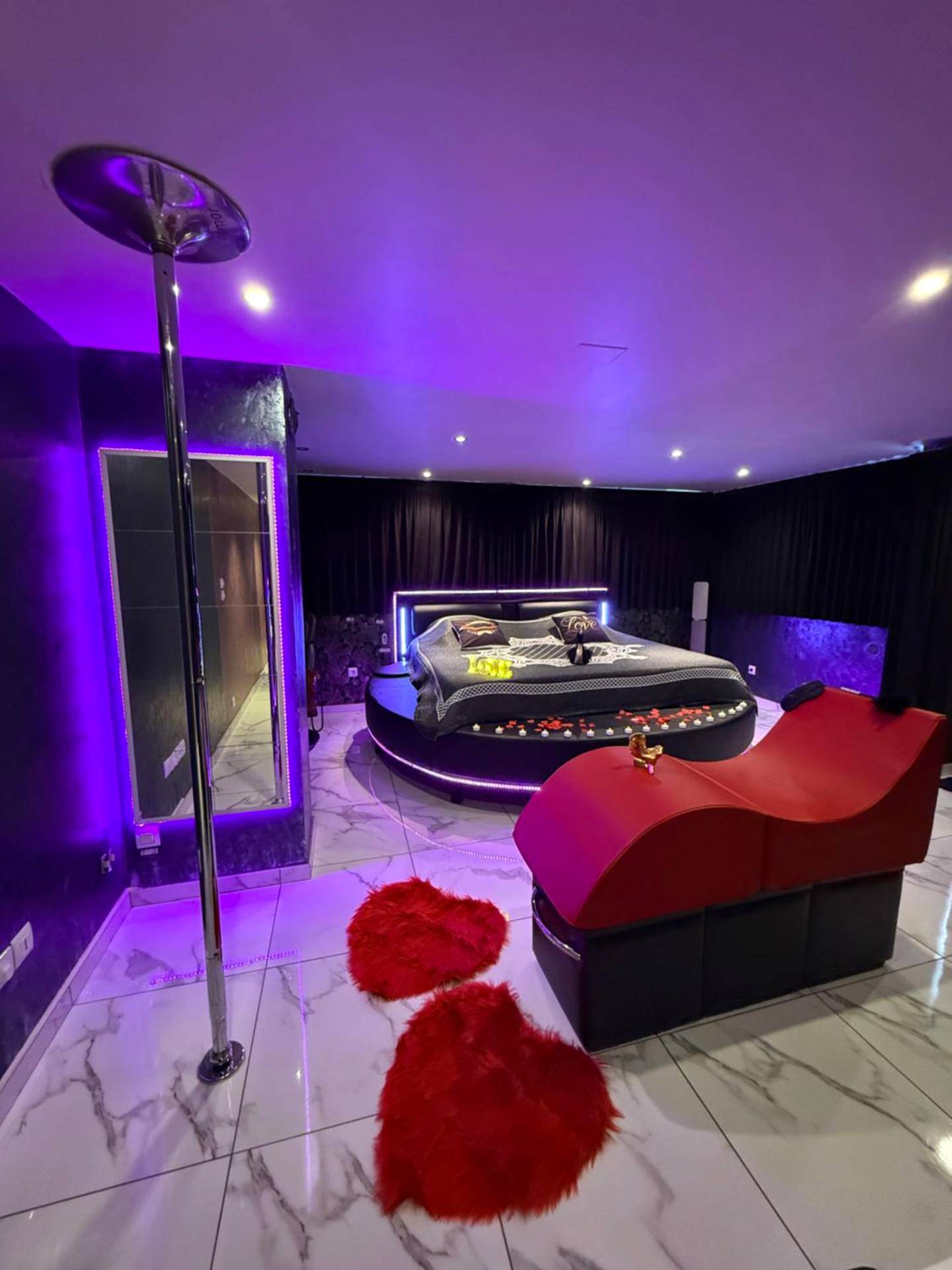 Chambre avec lit rond, barre de pole dance et sofa - Love Room Attitude