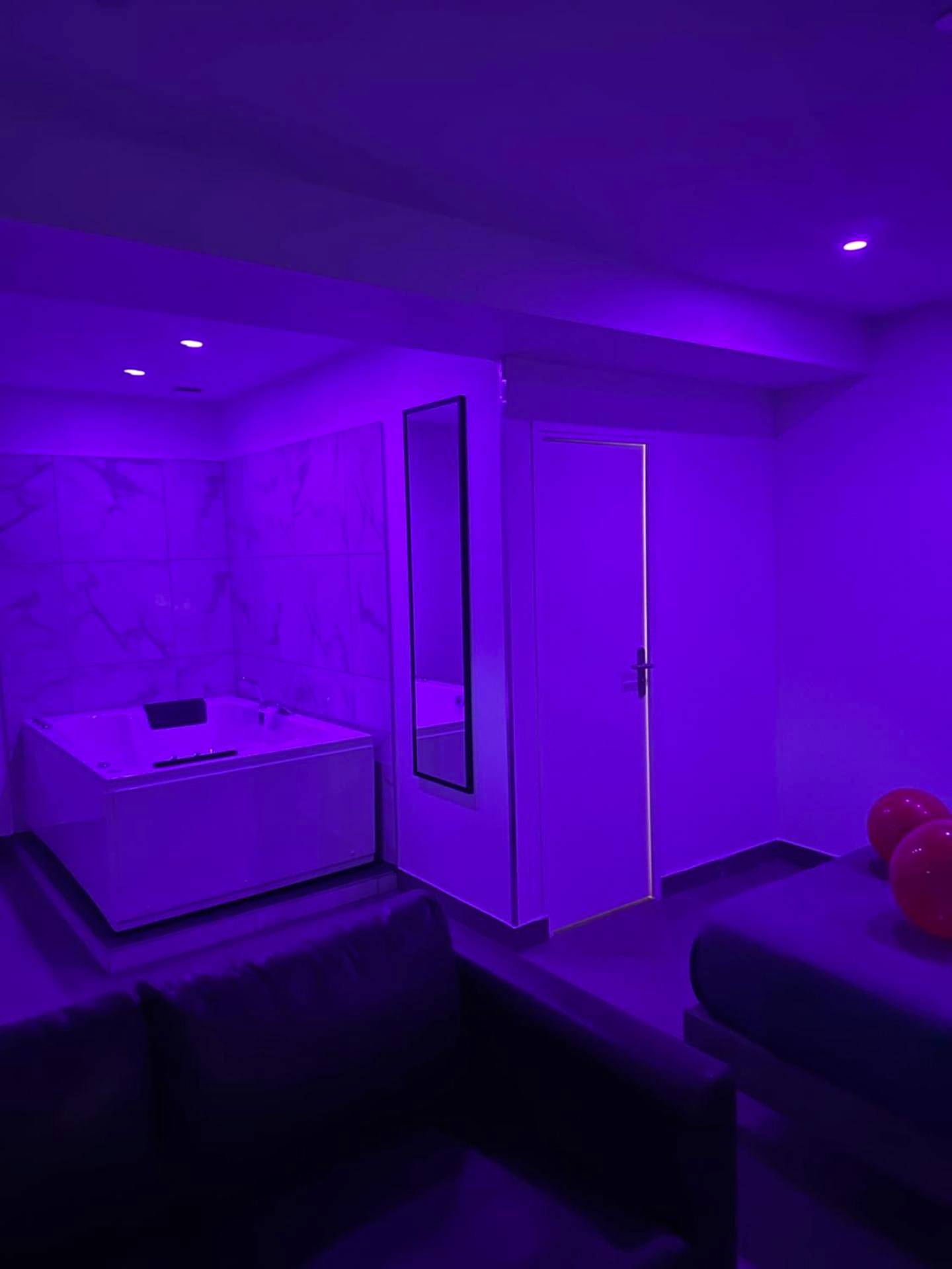 Jacuzzi privatif sous lumière néon violette - Love Room Fleury - Mérogis - Lov’SPA 2