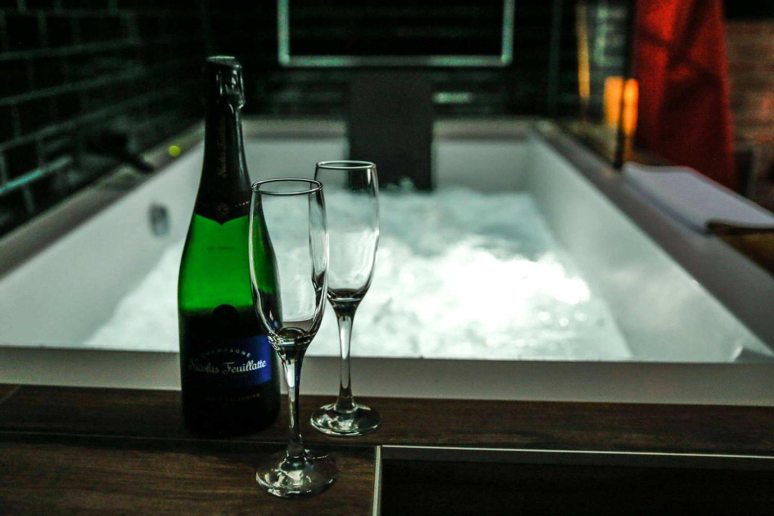 Bouteille de champagne et flûtes devant le spa - Love Room Condé - Sainte - Libiaire - Luxe and Spa