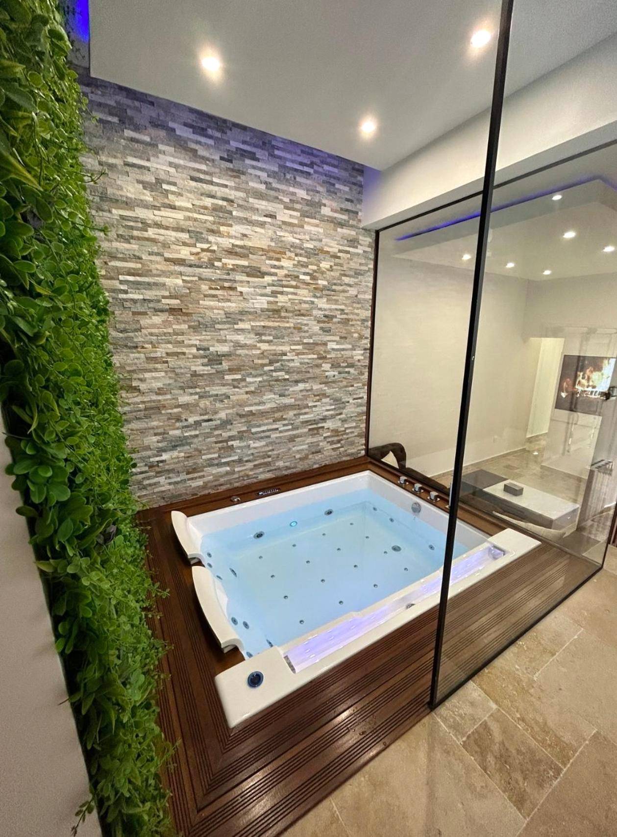 Jacuzzi encastré avec mur de pierre et verdure - Love Room Pierrefitte - sur - Seine - Maison Hanaa, Sauna & Spa
