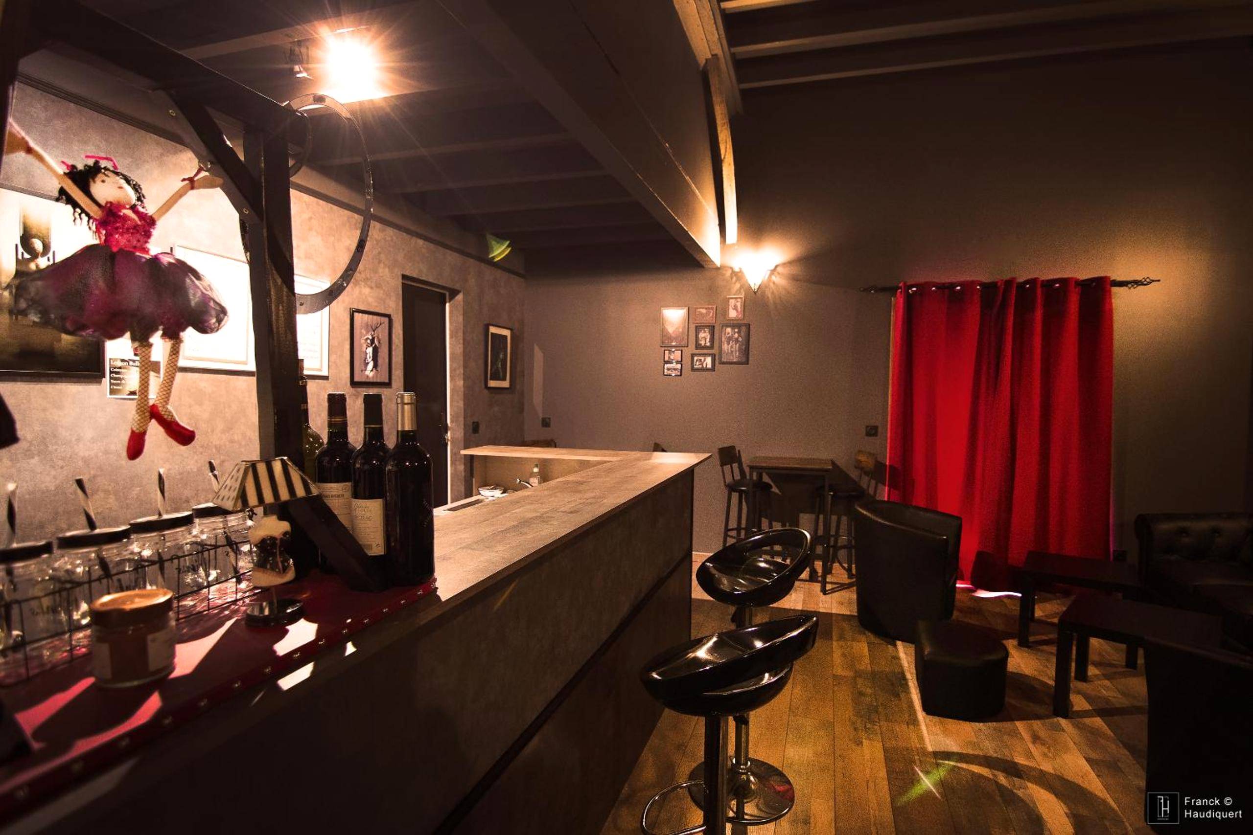 Espace bar avec tabourets et rideaux rouges - Maison des Soupirs