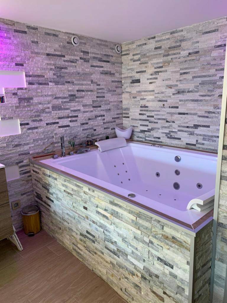 Baignoire balnéo avec mur en parement de pierre - Love Room Le Cendre - Le Menhir Jacuzzi Lit 200x200