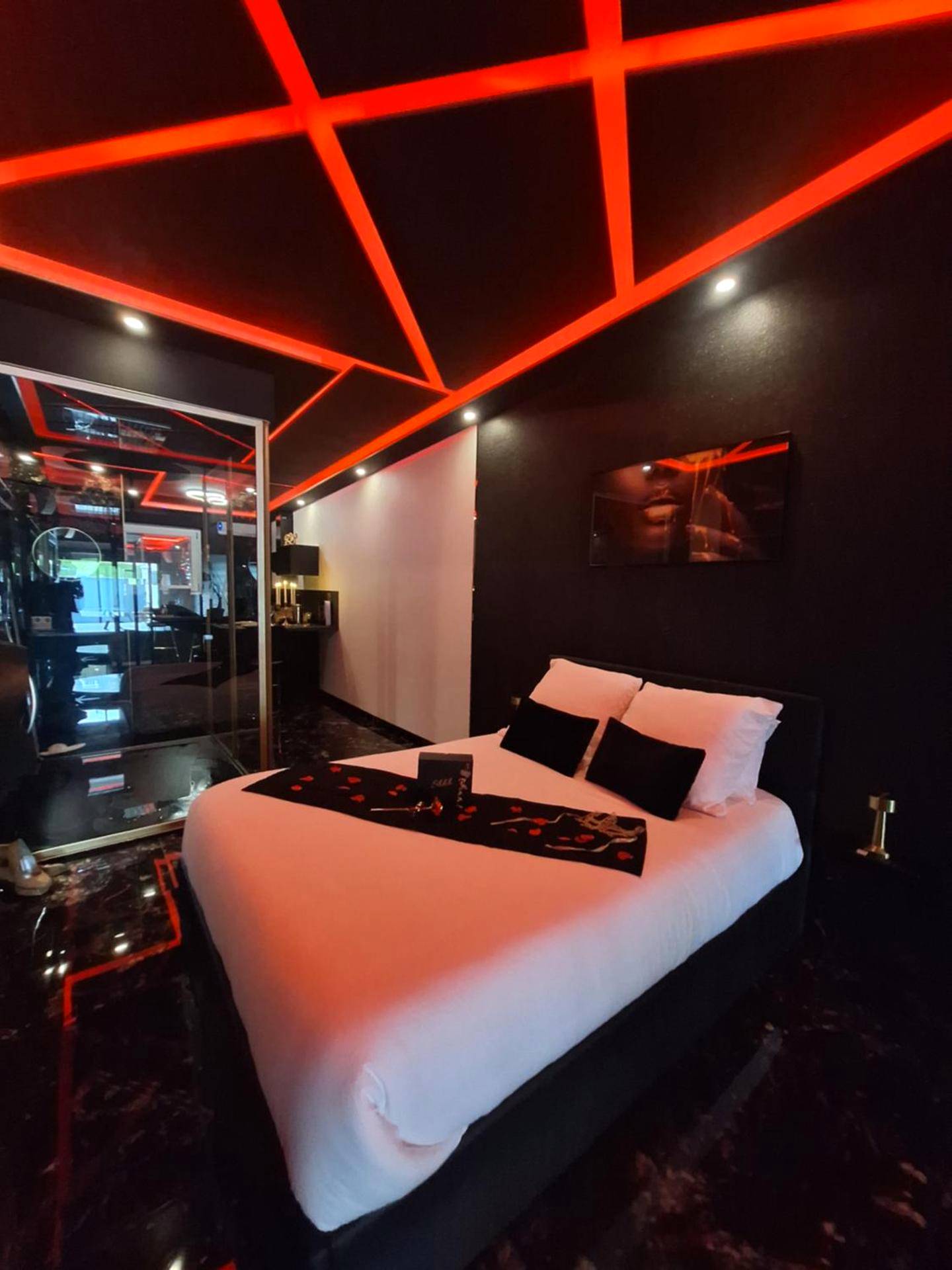 Lit double sous un plafond lumineux rouge - love room mes petits secrets miniac morvan avec jacuzzi privatif